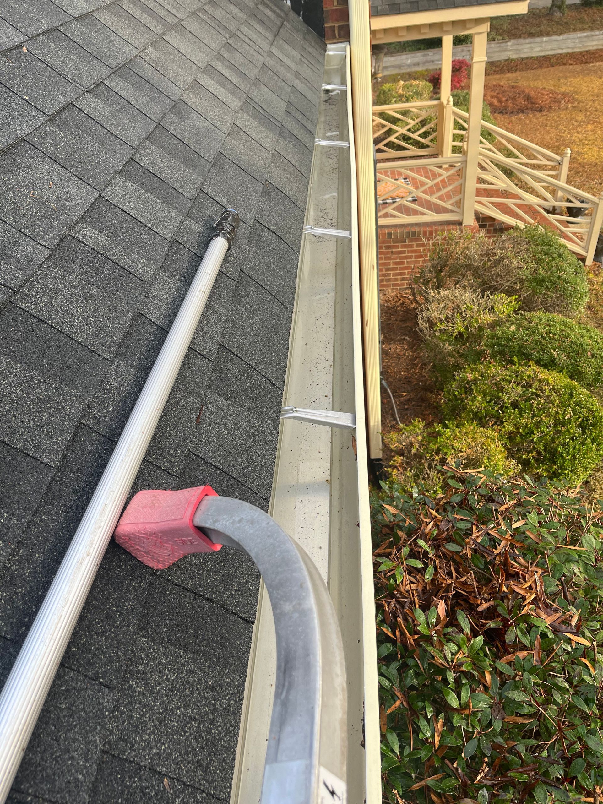 A person is cleaning a gutter on the side of a house.