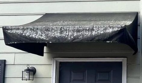 A black awning is over a door on a house.