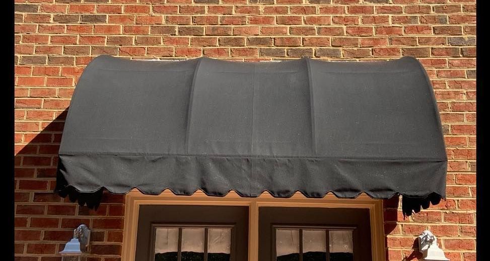 A black awning over a window on a brick building