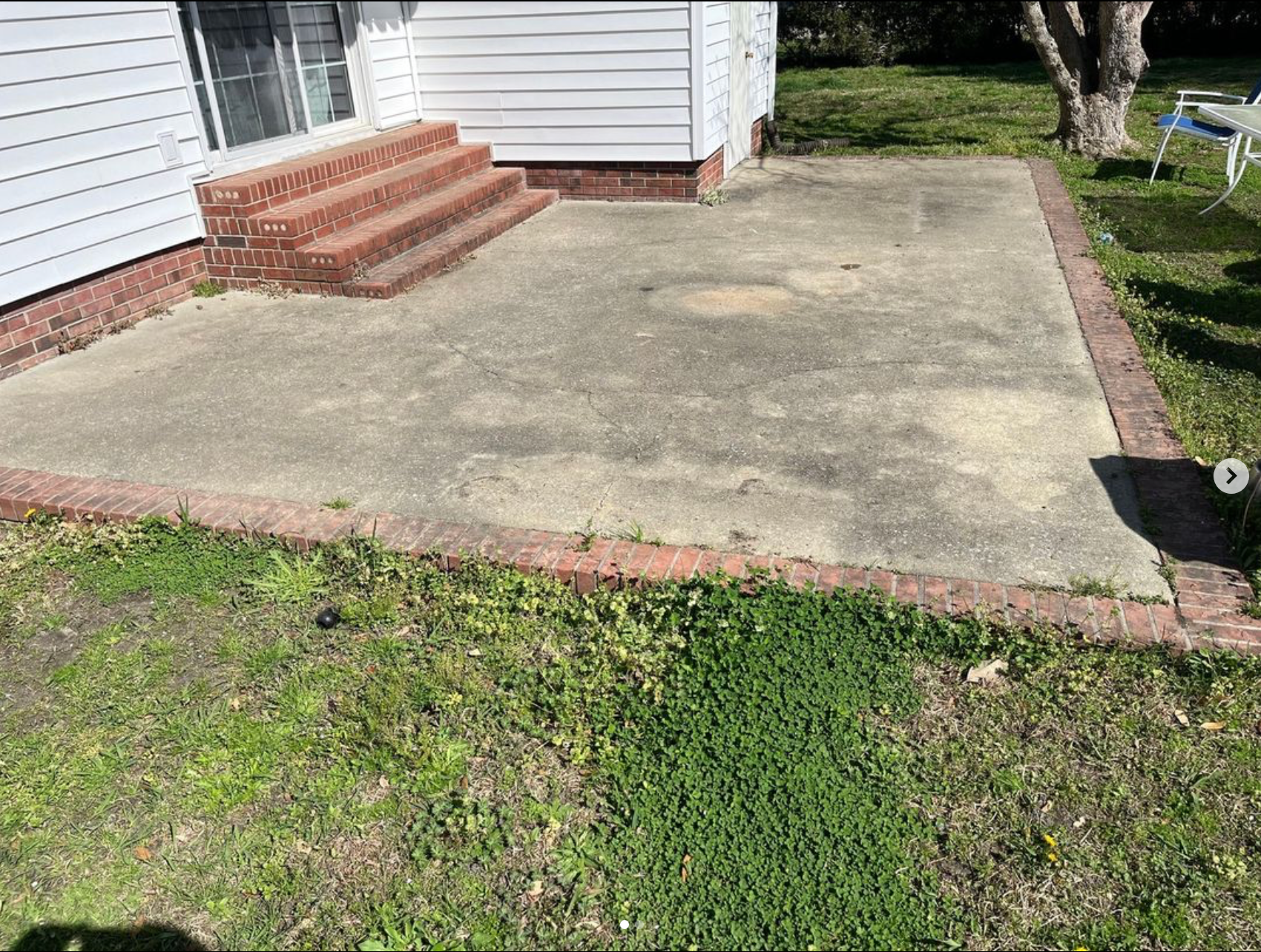 There is a wheelbarrow in the middle of the grass in the backyard.