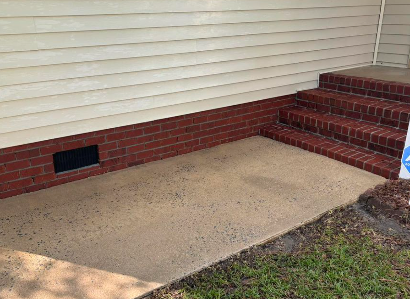 A brick wall with stairs leading up to it and a sign in front of it.