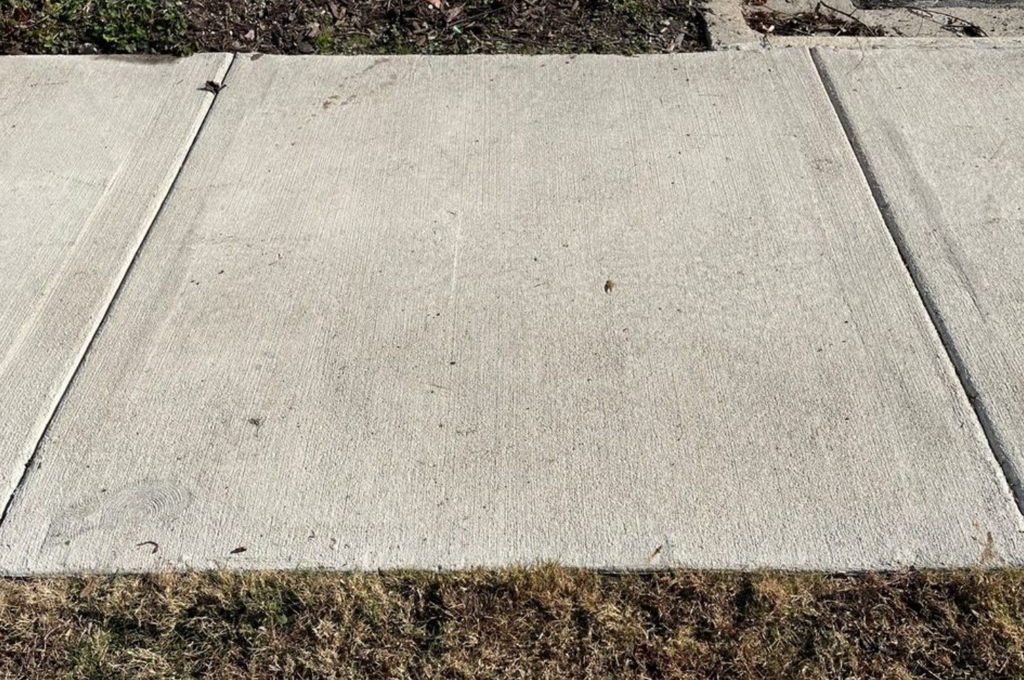 A close up of a concrete sidewalk with grass on the side.