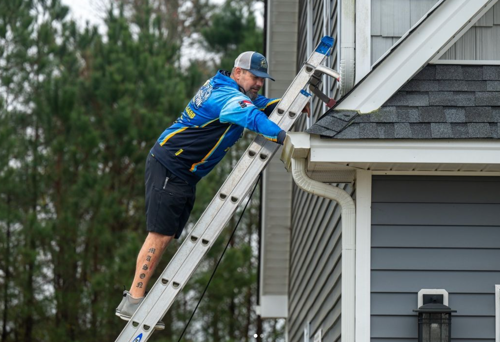 A man is standing on a ladder next to a house.