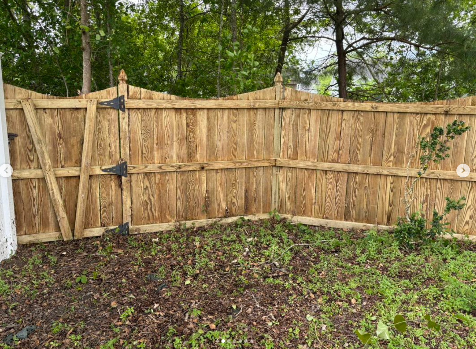 A wooden fence is sitting in the middle of a lush green field.