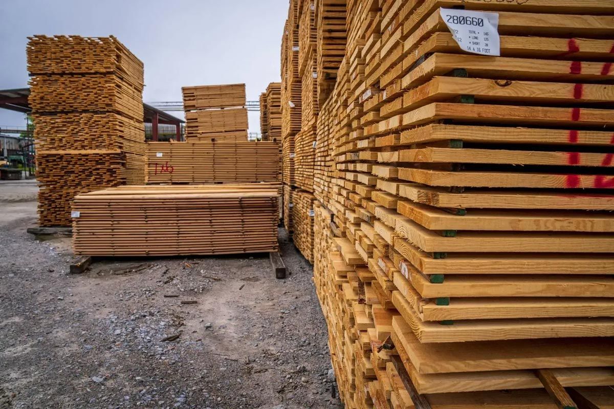 Stacks of wooden planks in an outdoor lumberyard setting.