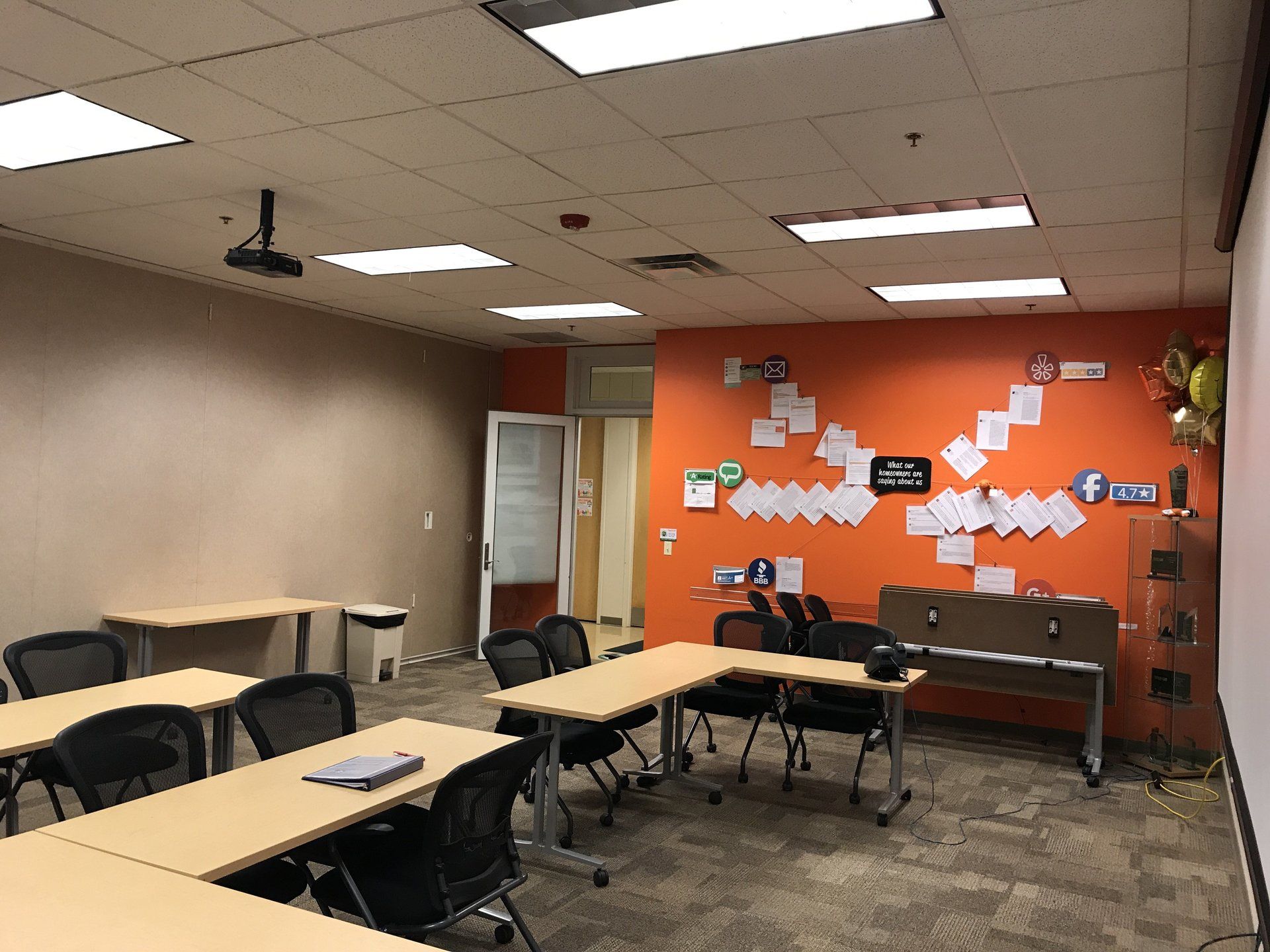A classroom with tables and chairs and an orange wall.