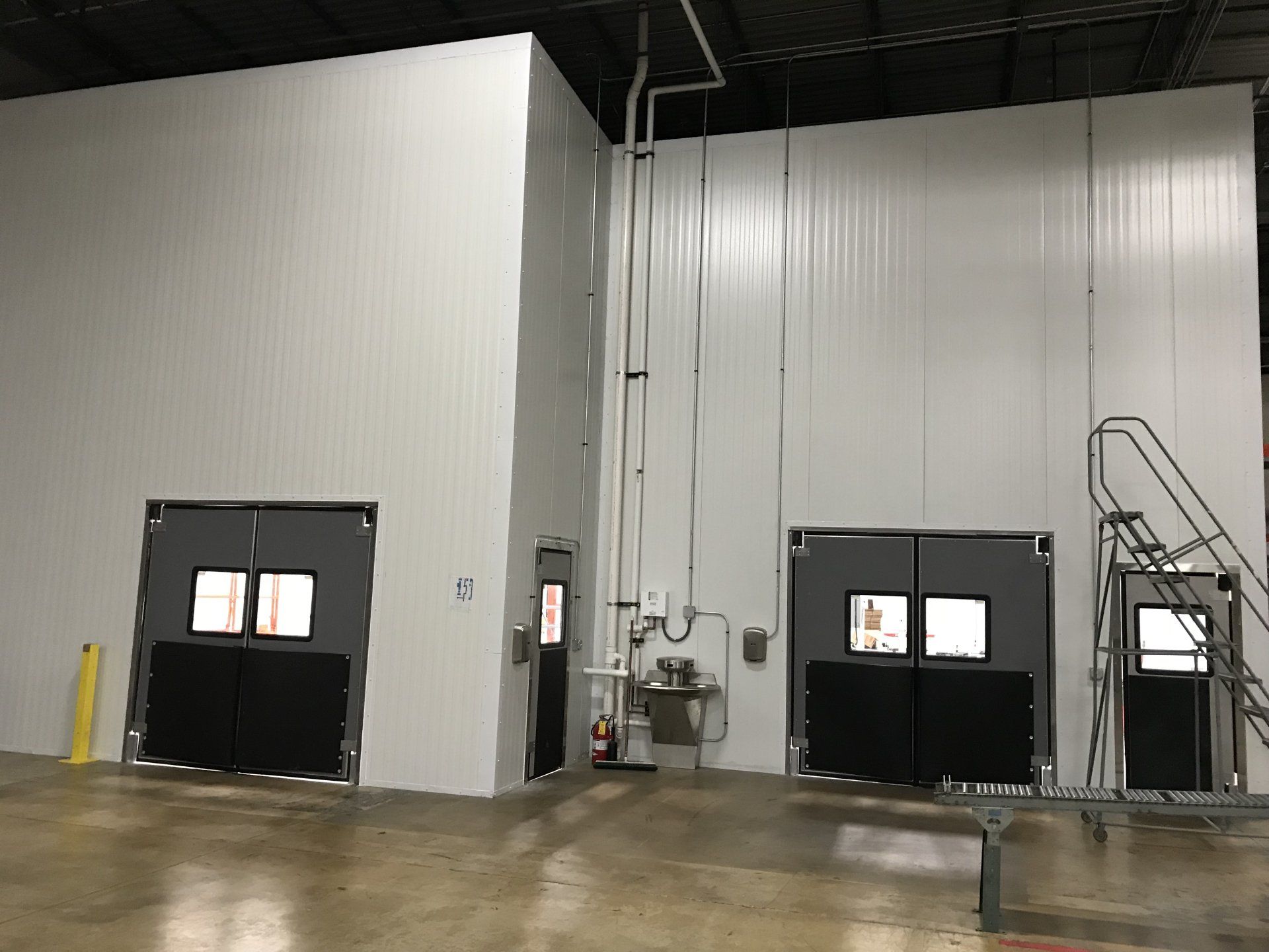 A warehouse with a lot of doors and a ladder.