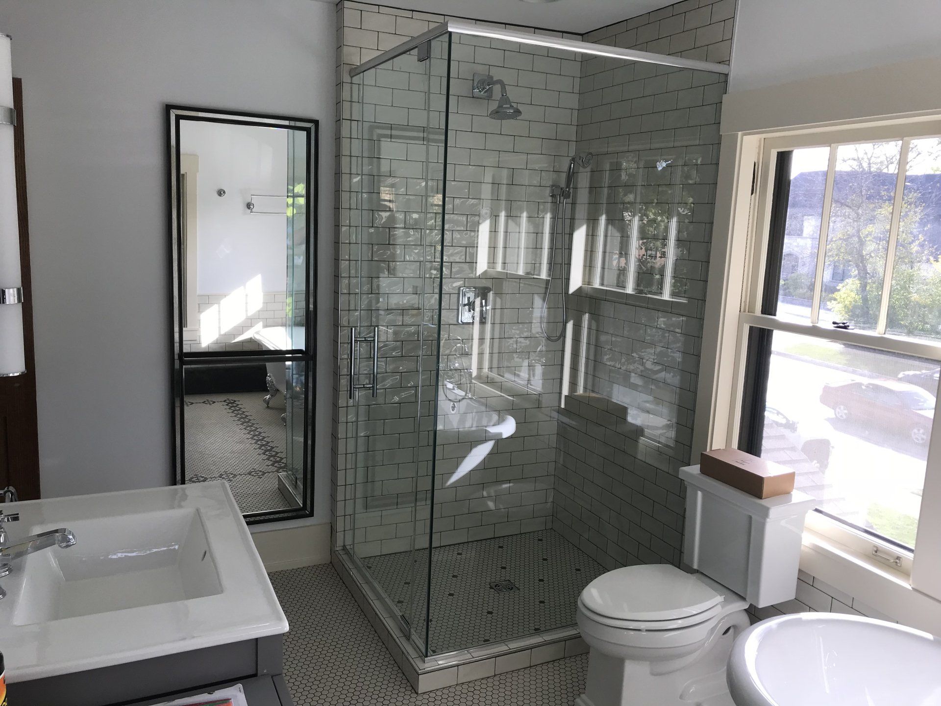 A bathroom with a toilet , sink , shower and mirror.