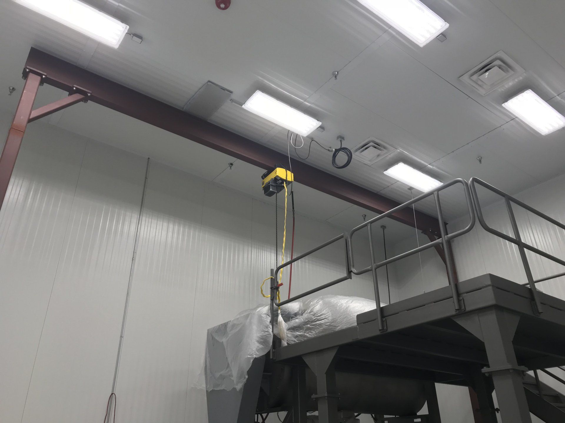 A machine is being lifted by a crane in a room.