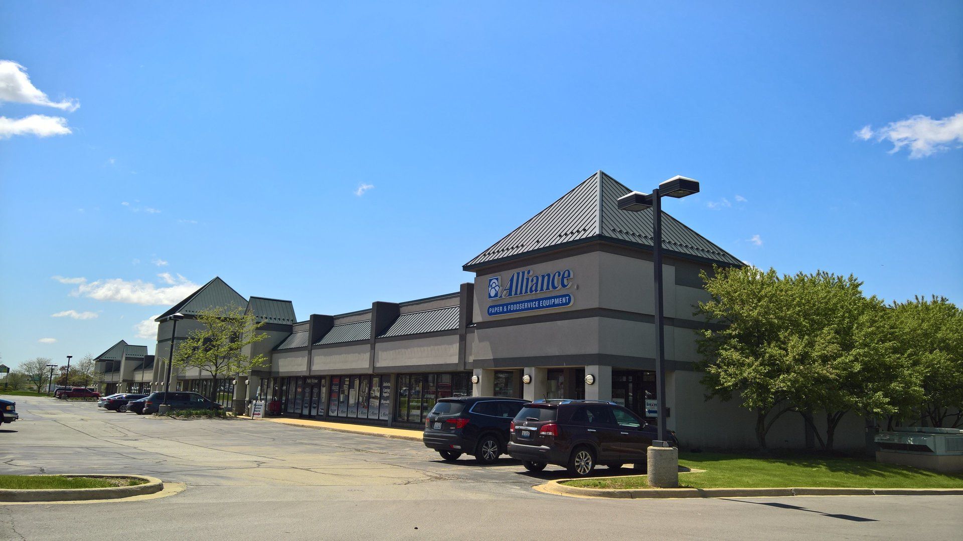 A group of cars are parked in front of a building that says ' a & a ' on it.