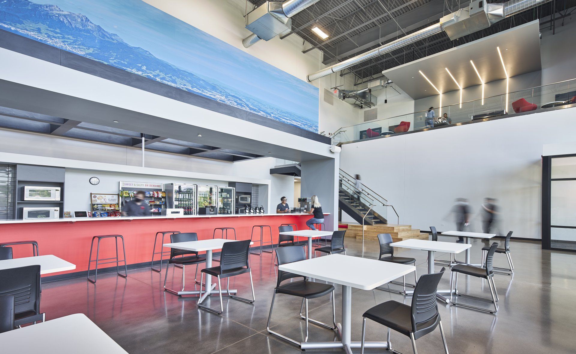 A large dining room with tables and chairs and a bar.