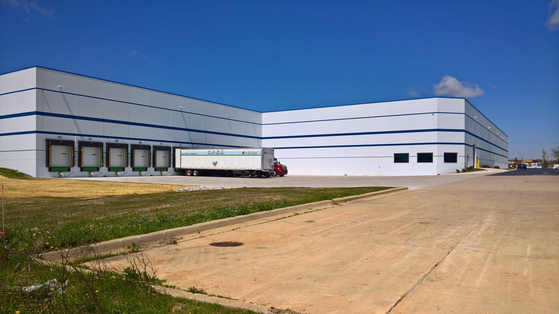A truck is parked in front of a large white building.