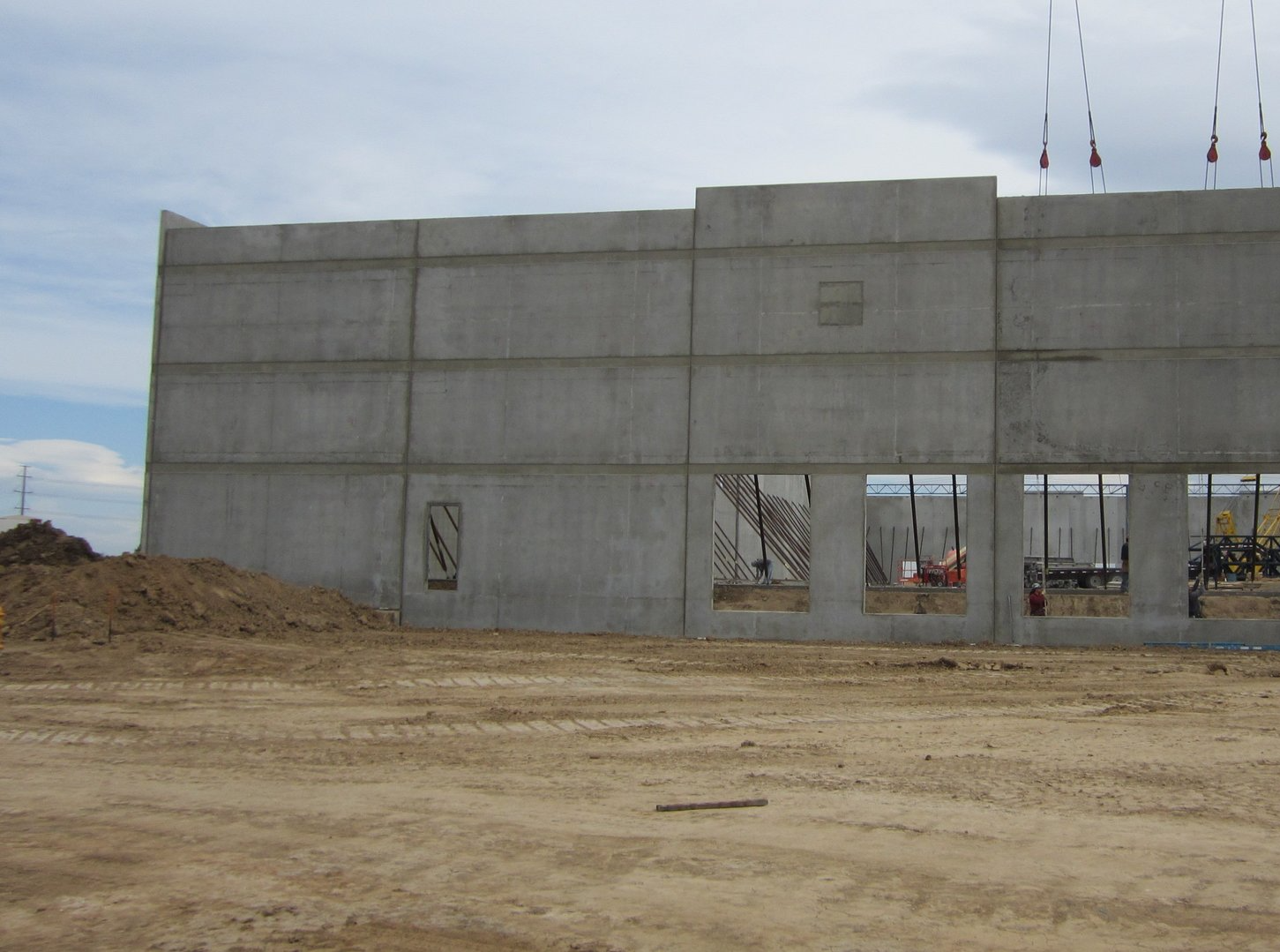 A large concrete building is being built in a dirt field
