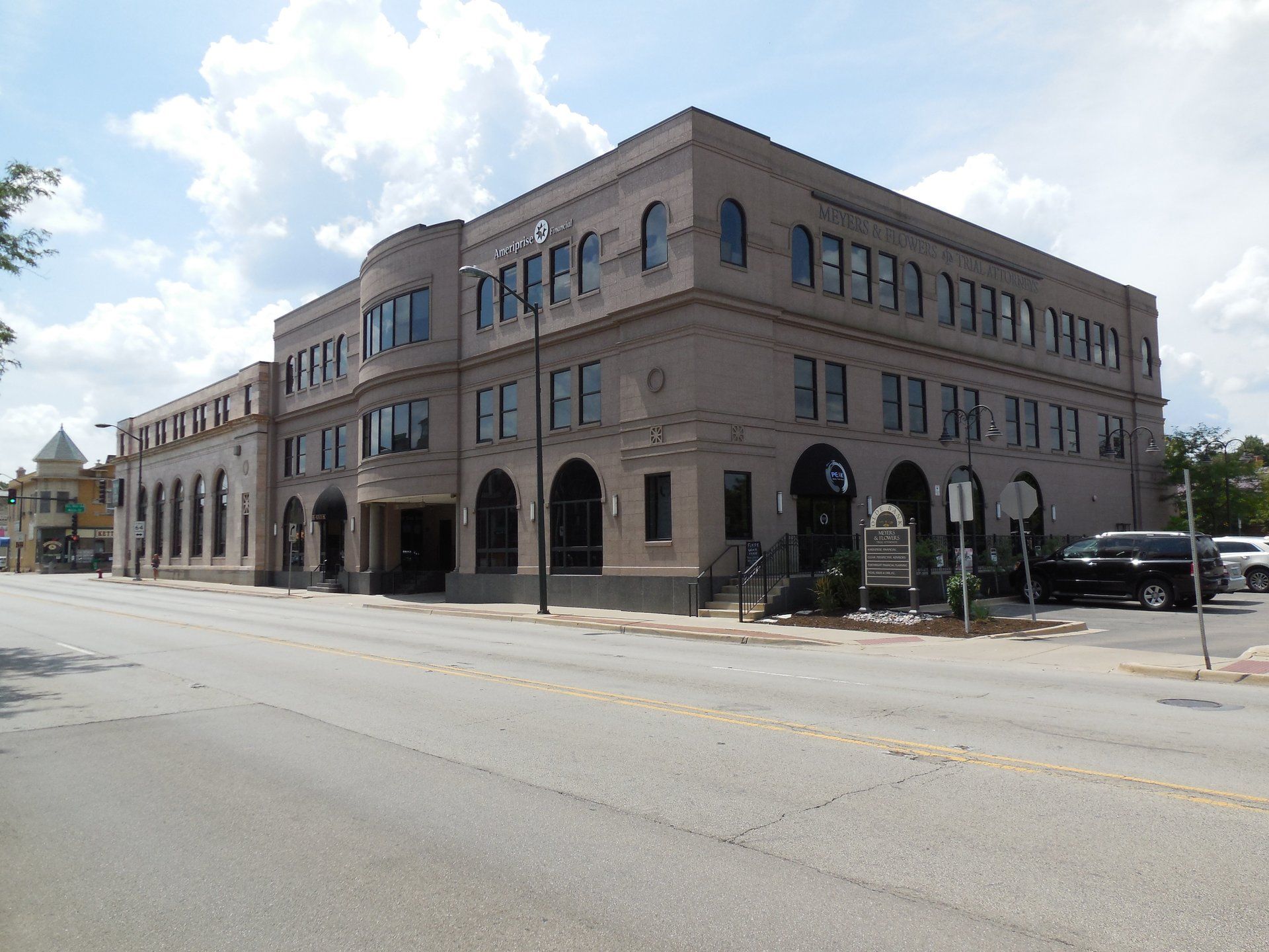 A large building on the corner of a street with cars parked in front of it