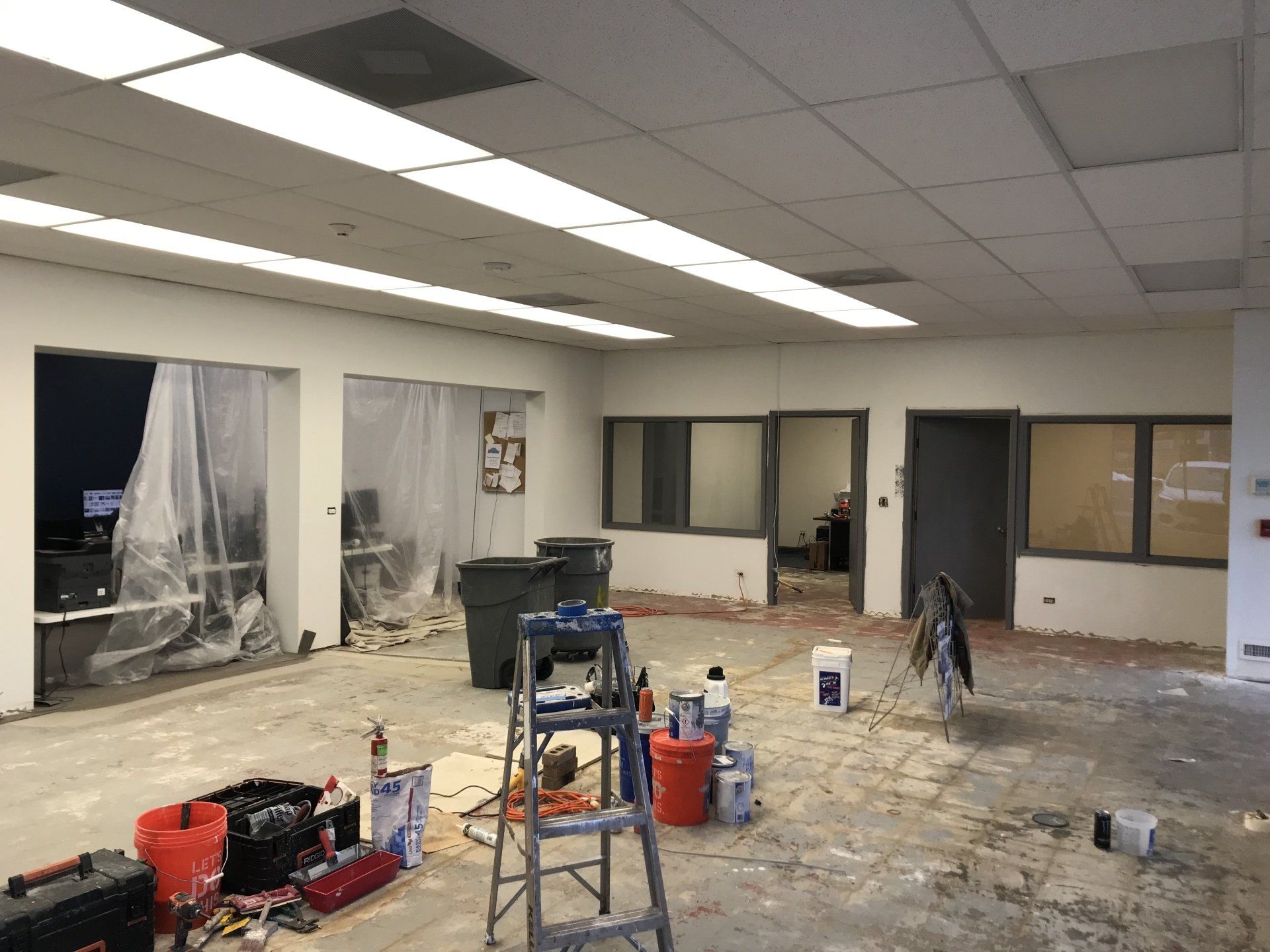 An empty room with a ladder and buckets of paint.