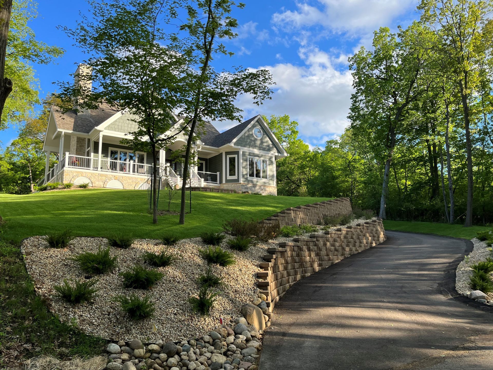 A large white house is sitting on top of a lush green hill surrounded by trees.