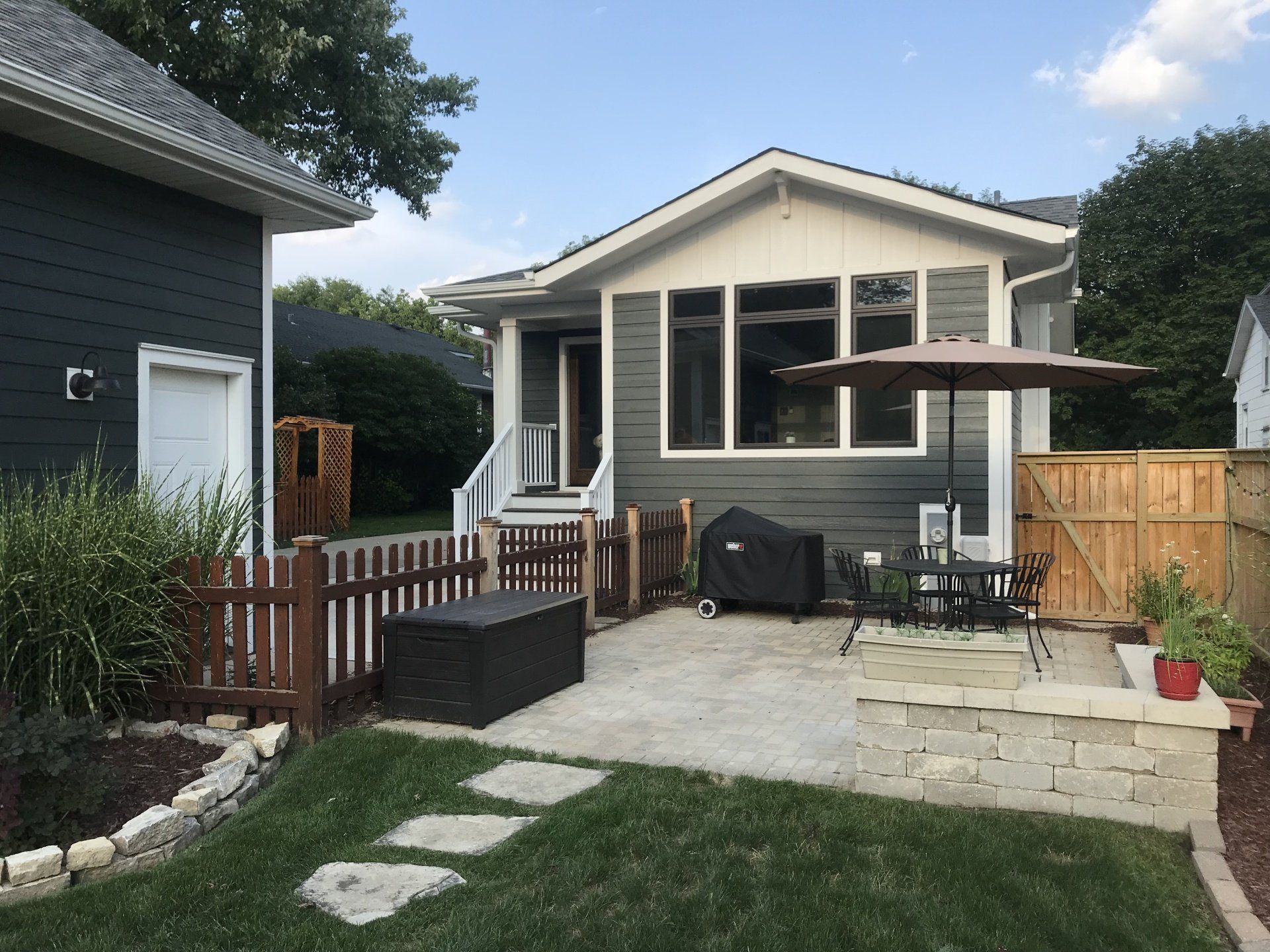 A house with a patio and umbrella in front of it.
