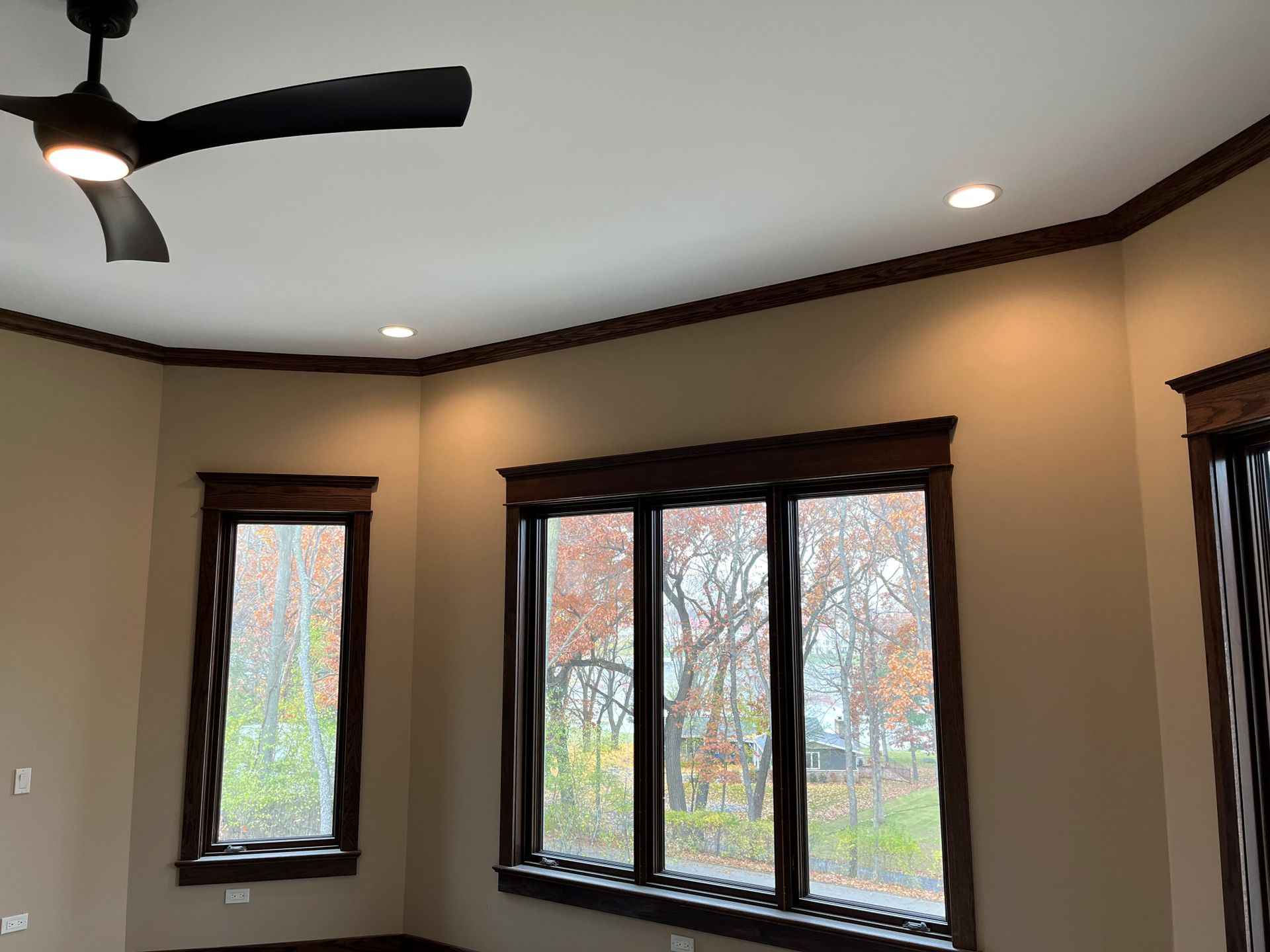 A room with two windows and a ceiling fan.