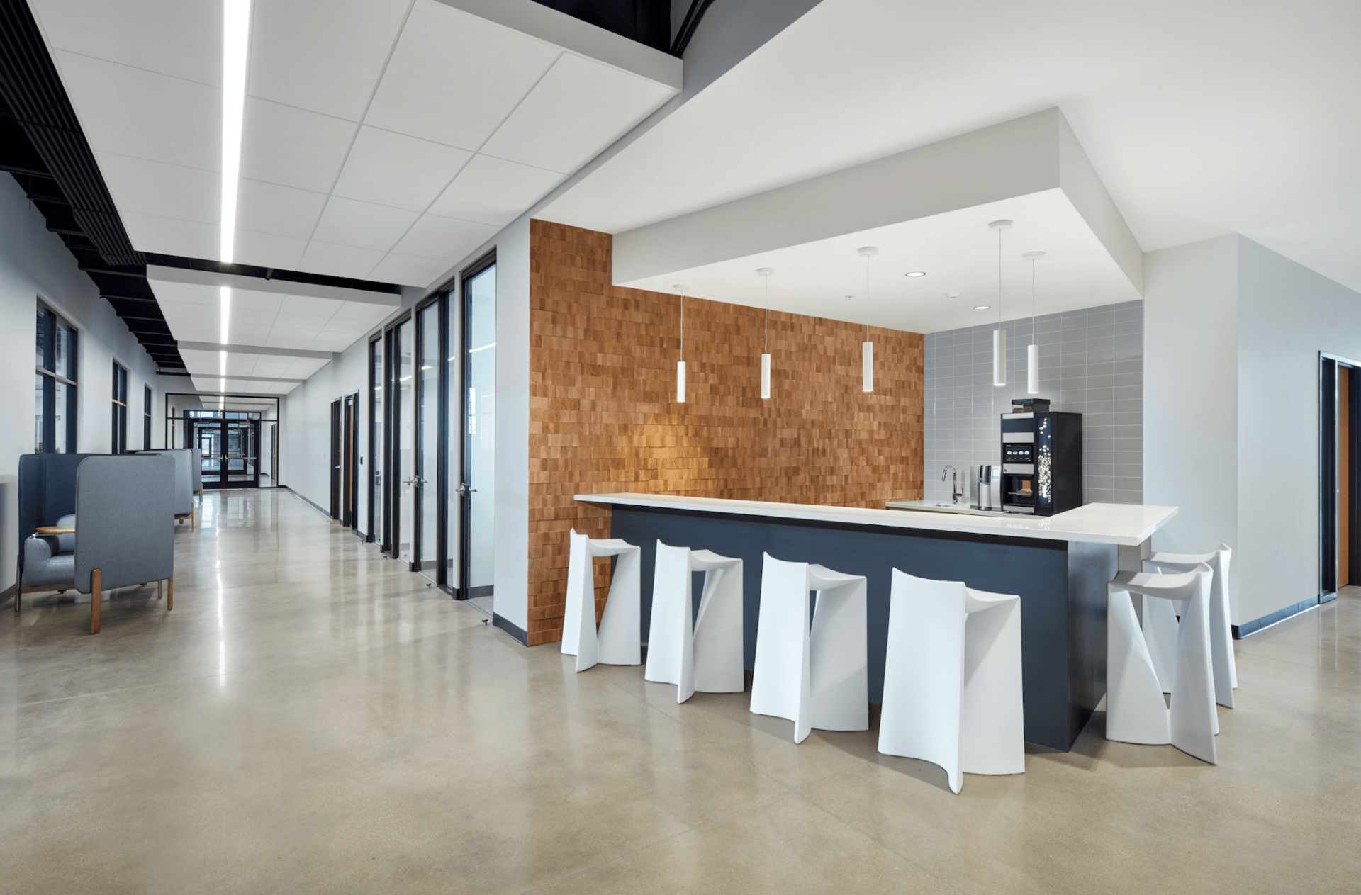 A long hallway with a bar and stools in the middle of it.