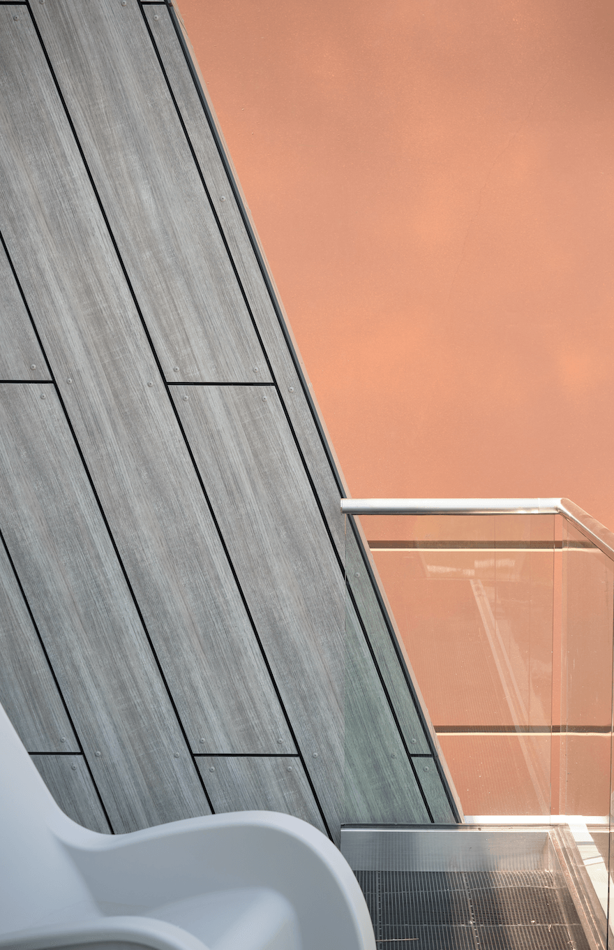 A white chair is sitting in front of a wooden wall.
