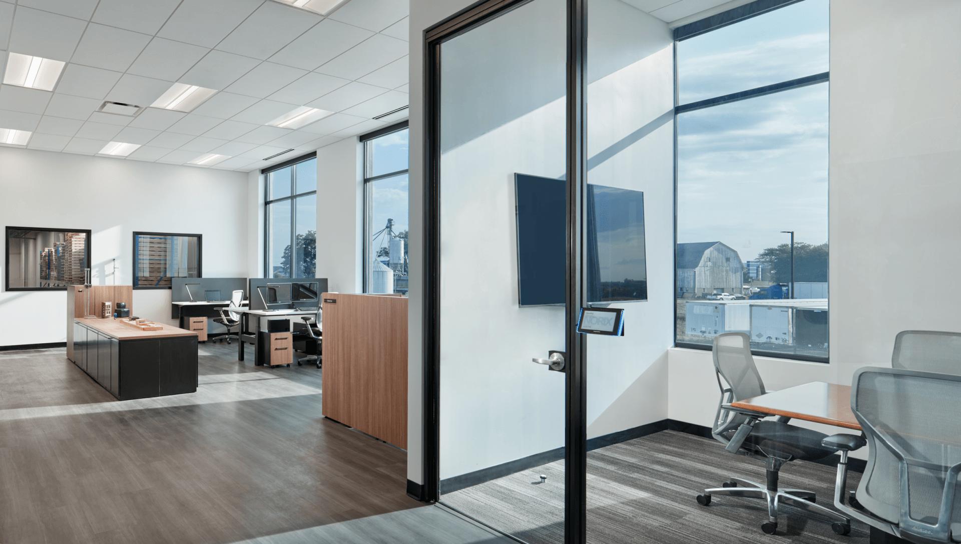 A large office with a lot of windows , desks and chairs.