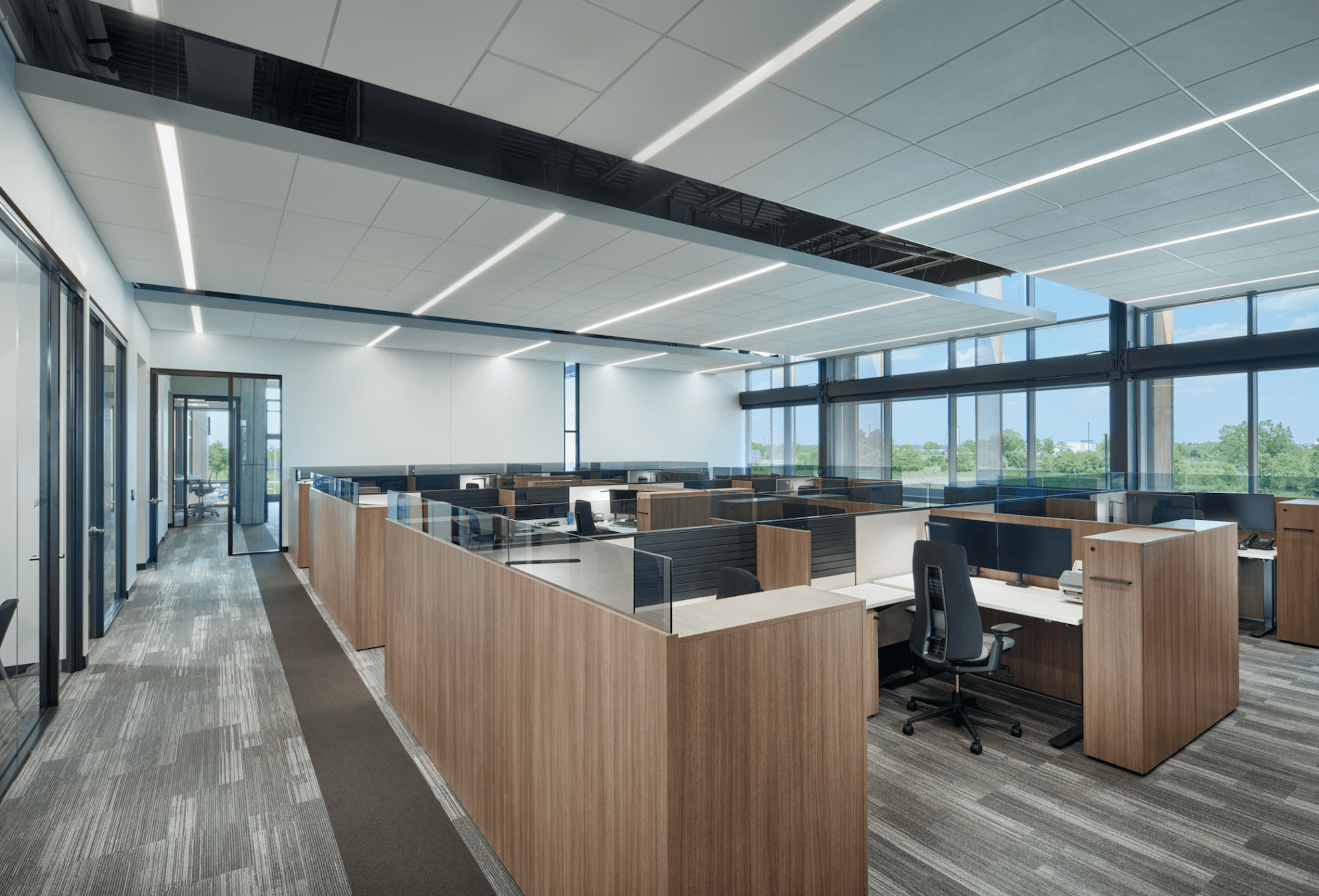 A large office with lots of desks and chairs and a lot of windows.