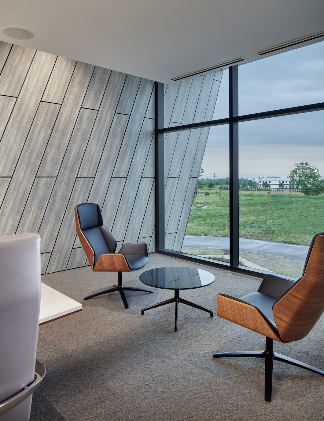 A room with two chairs and a table in front of a large window.