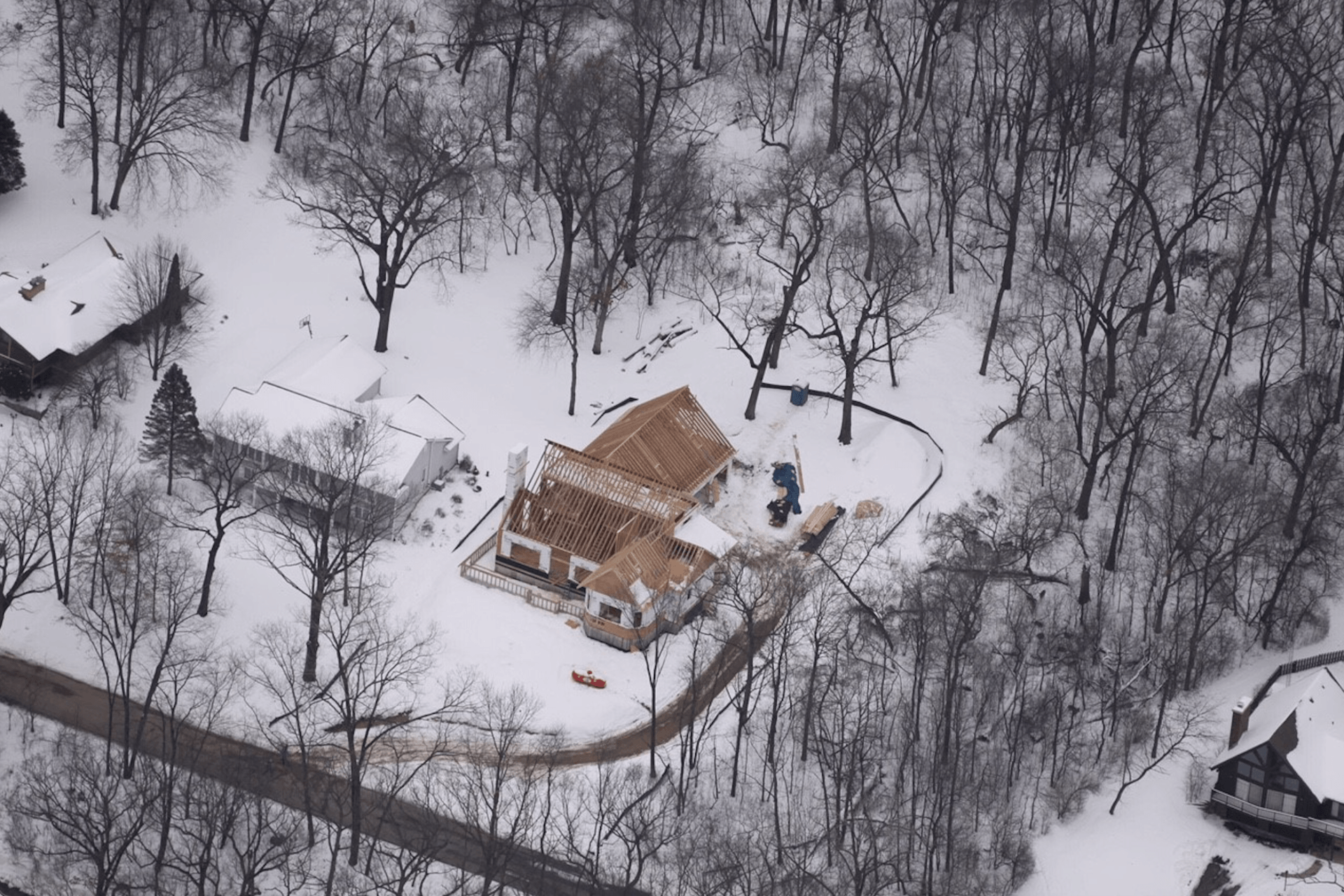 An aerial view of a house in the middle of a snowy forest