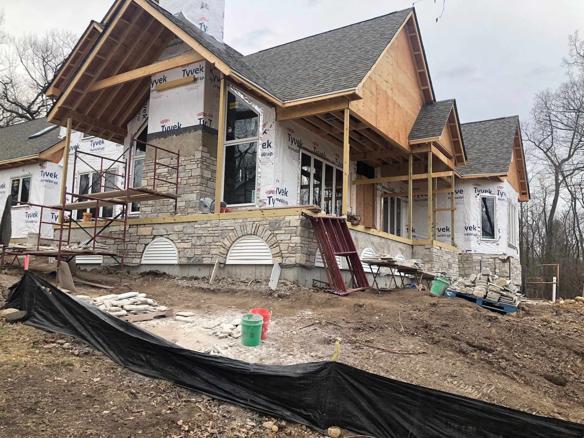 A large house is being built in the middle of a dirt field.