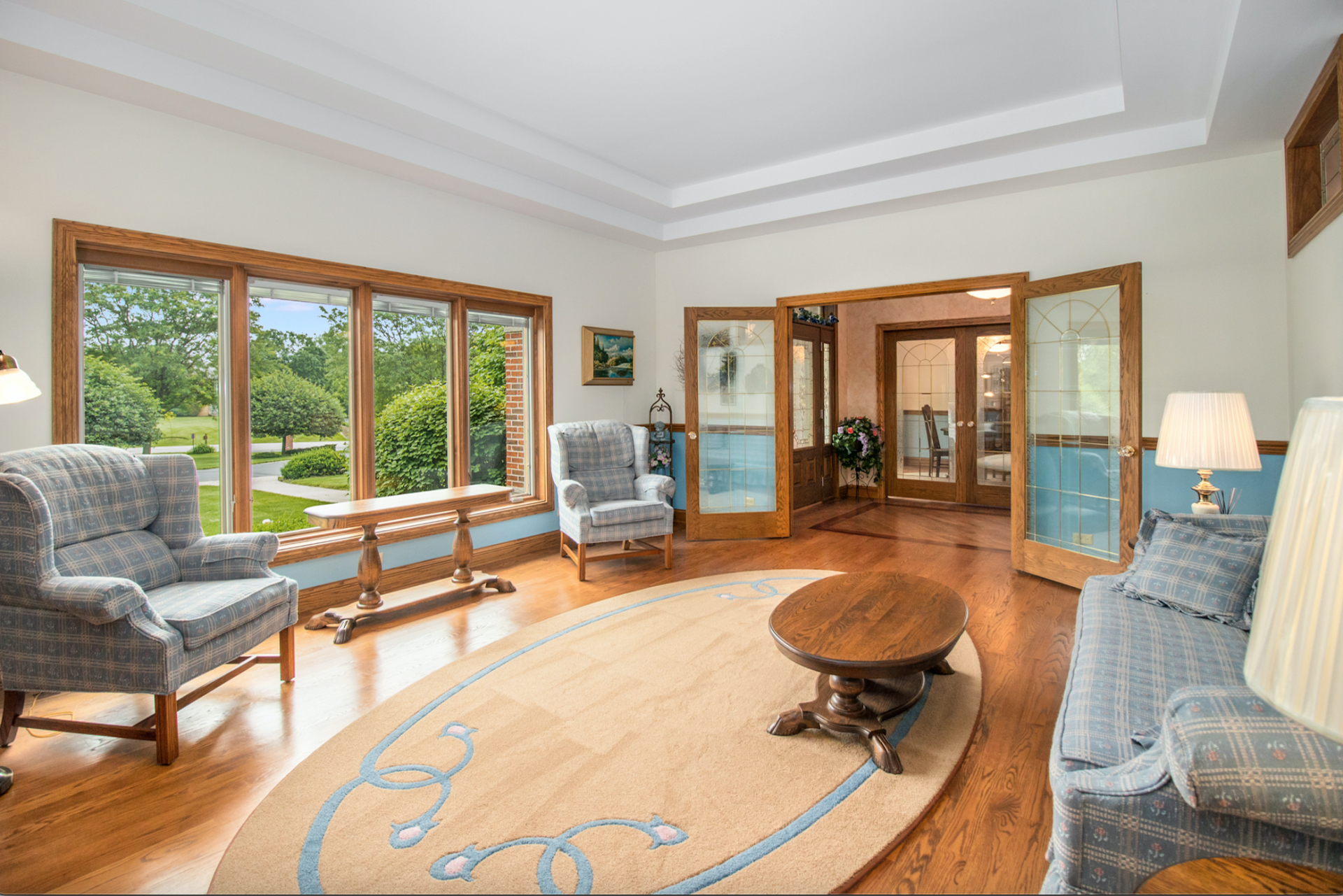 A living room with a couch , chairs , a table and a rug.
