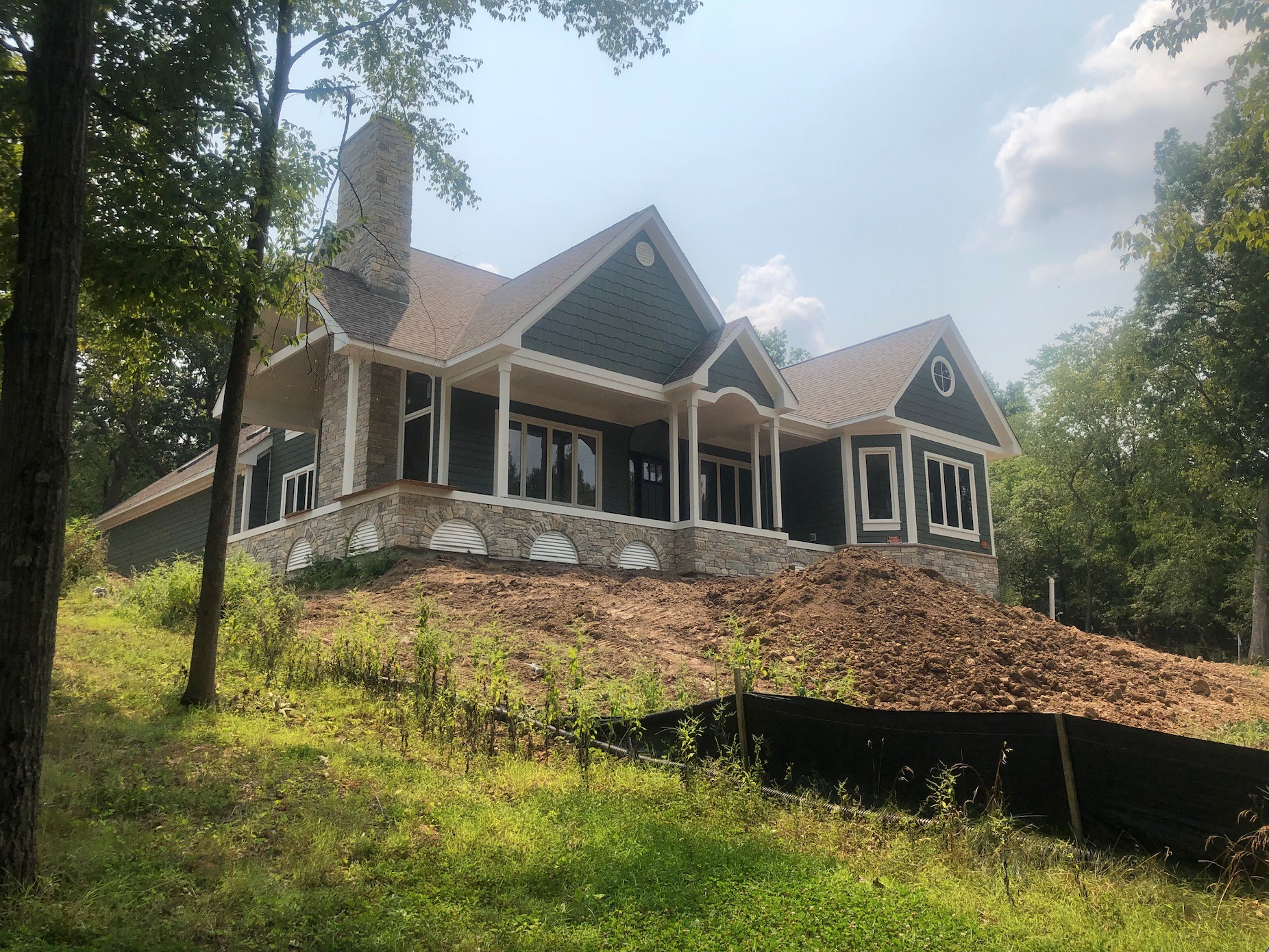 A large house is sitting on top of a hill surrounded by trees.