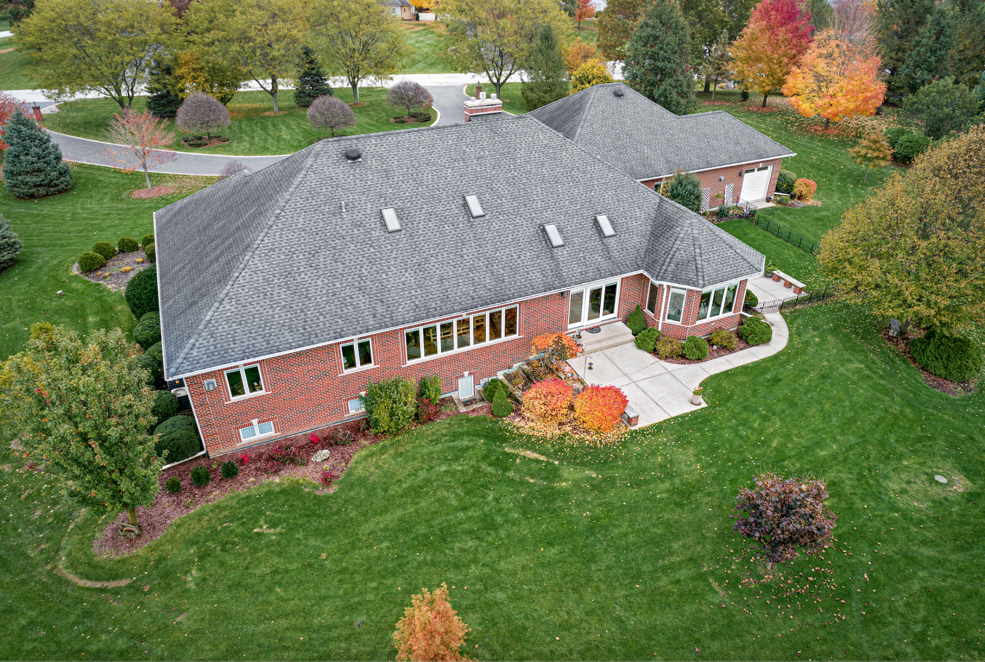 An aerial view of a large brick house surrounded by trees and grass.