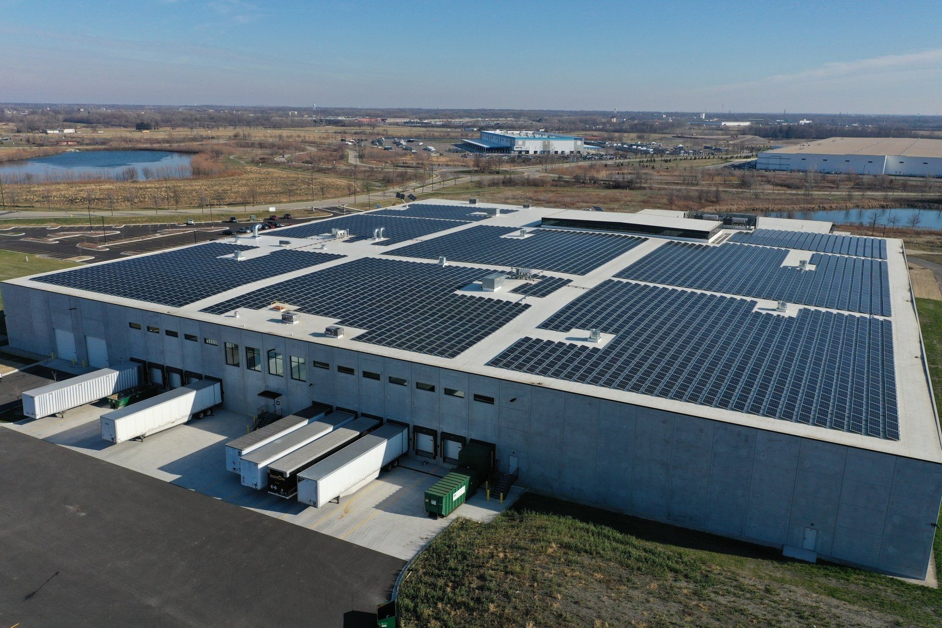 An aerial view of a large warehouse with a lot of solar panels on the roof.