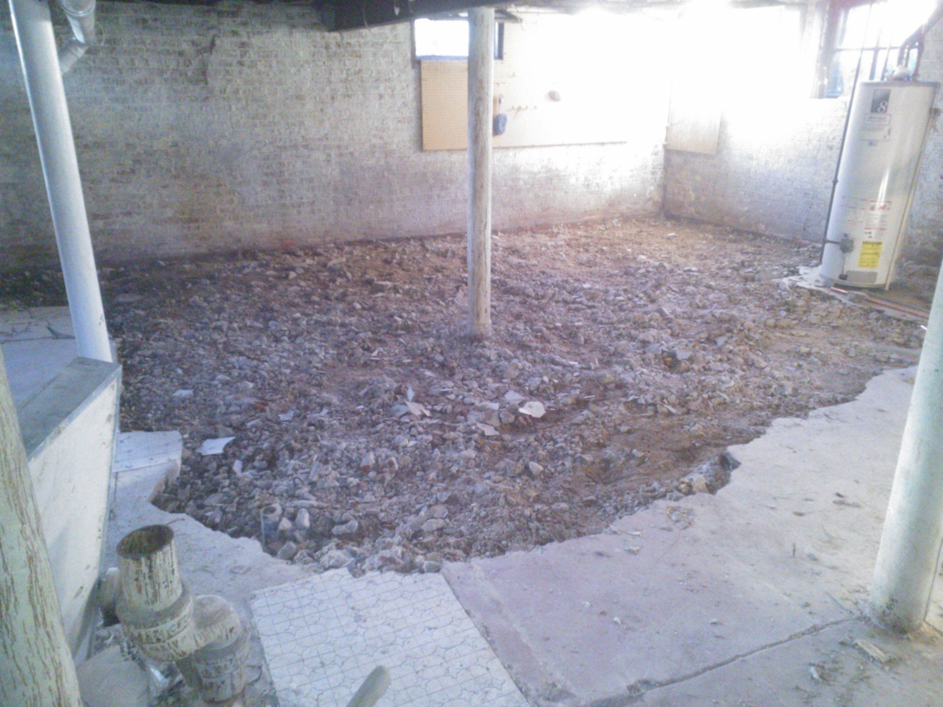 There is a hole in the floor of a basement.