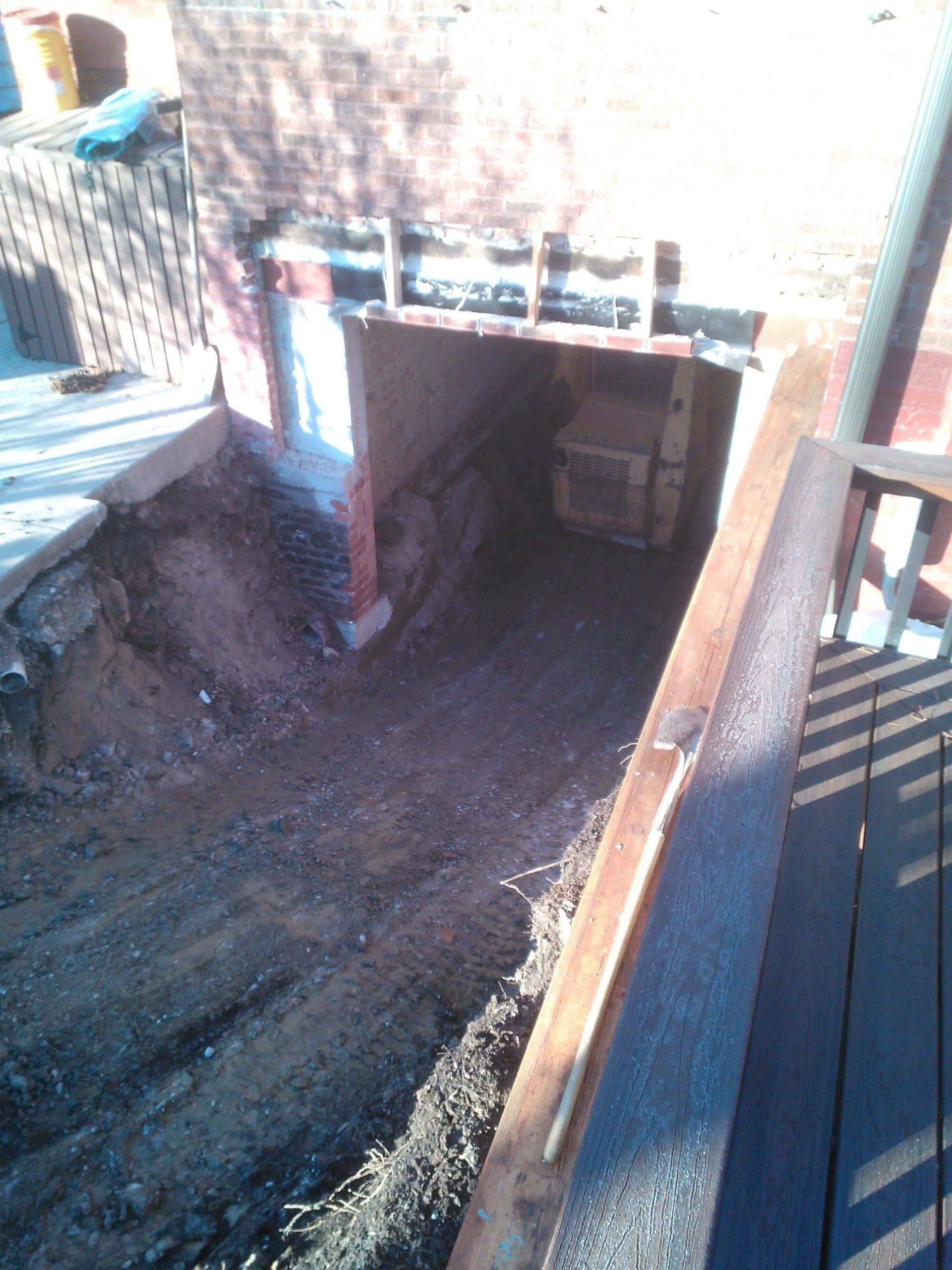 A hole in the ground with a wooden railing leading to it