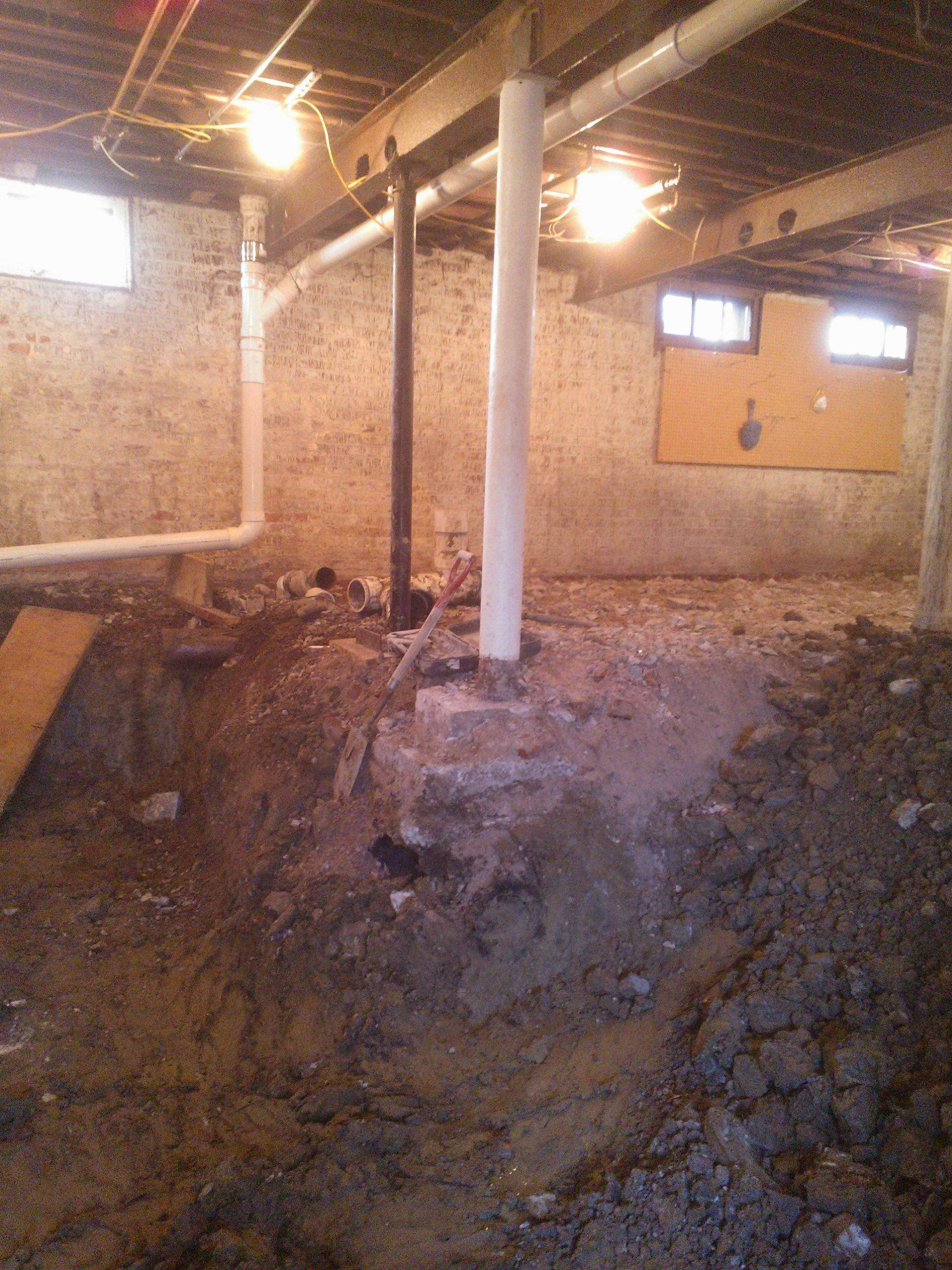 A basement with a lot of dirt and pipes in it.