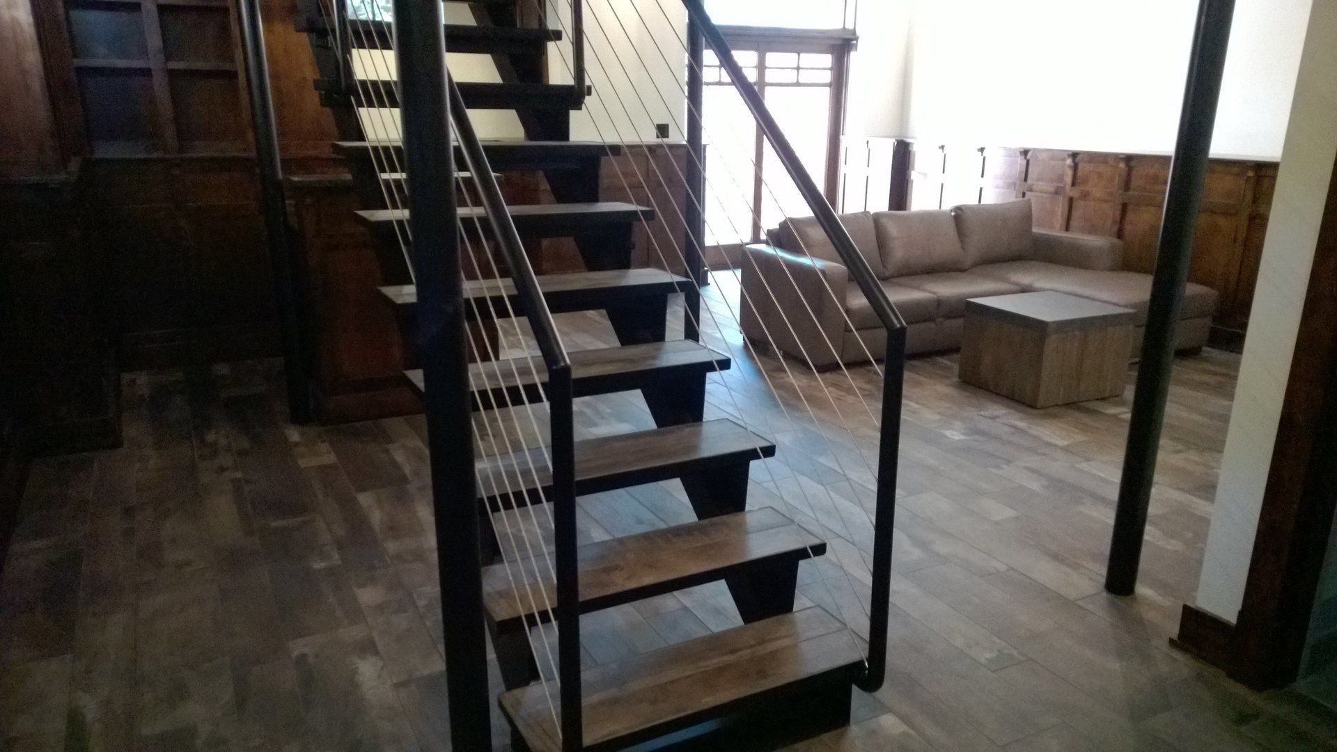 A wooden staircase with a metal railing in a living room