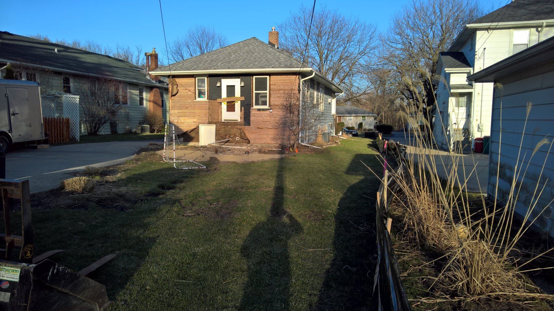 A shadow of a person is cast on the grass in front of a house
