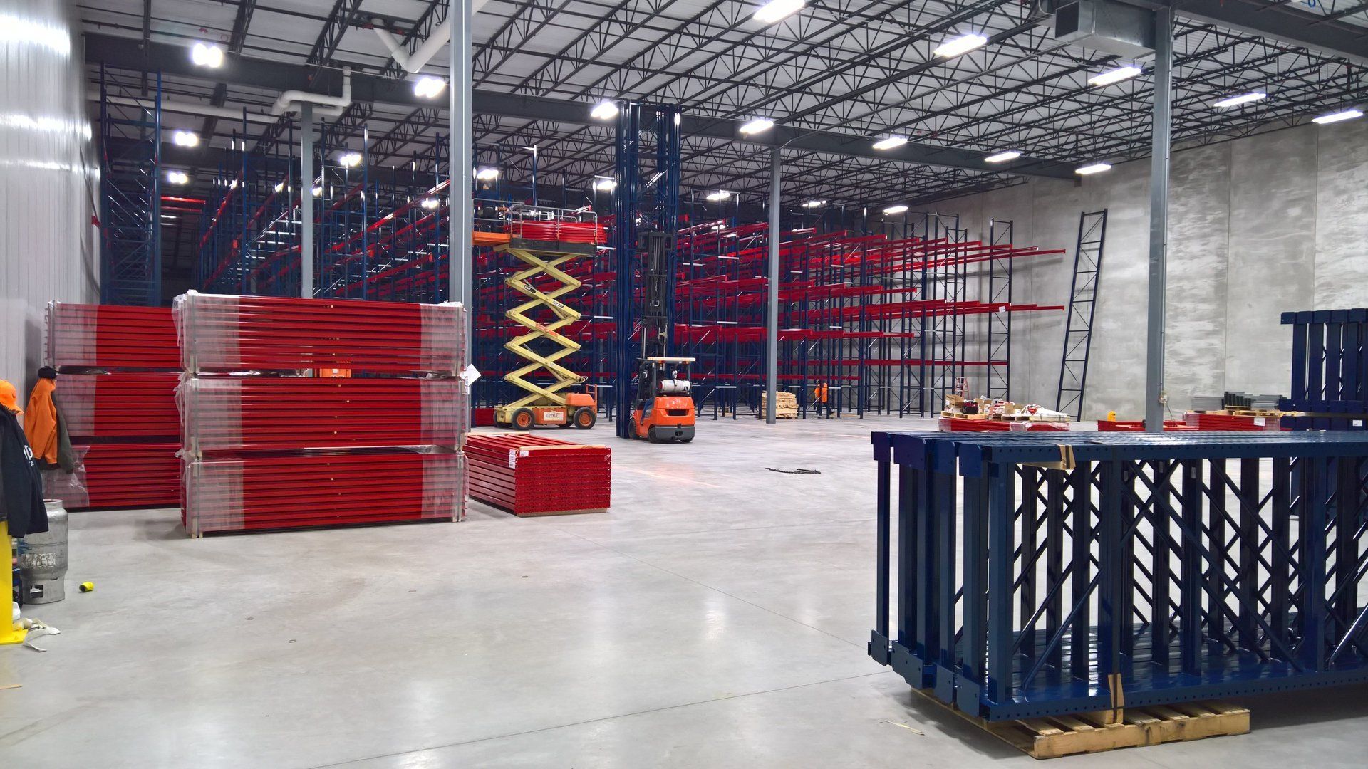 A large warehouse with a lot of shelves and a lift.