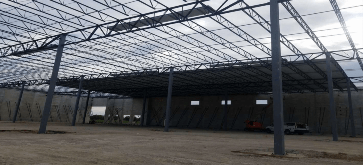 A large metal structure is being built in the middle of a dirt field.