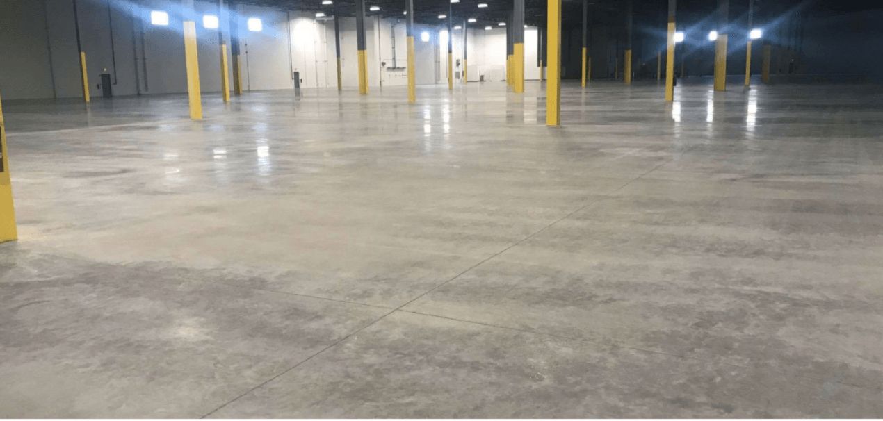 A large empty warehouse with a concrete floor and yellow poles.