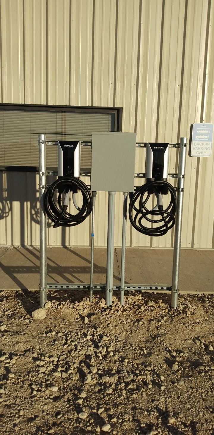 Two electric vehicle charging stations are sitting in front of a building.