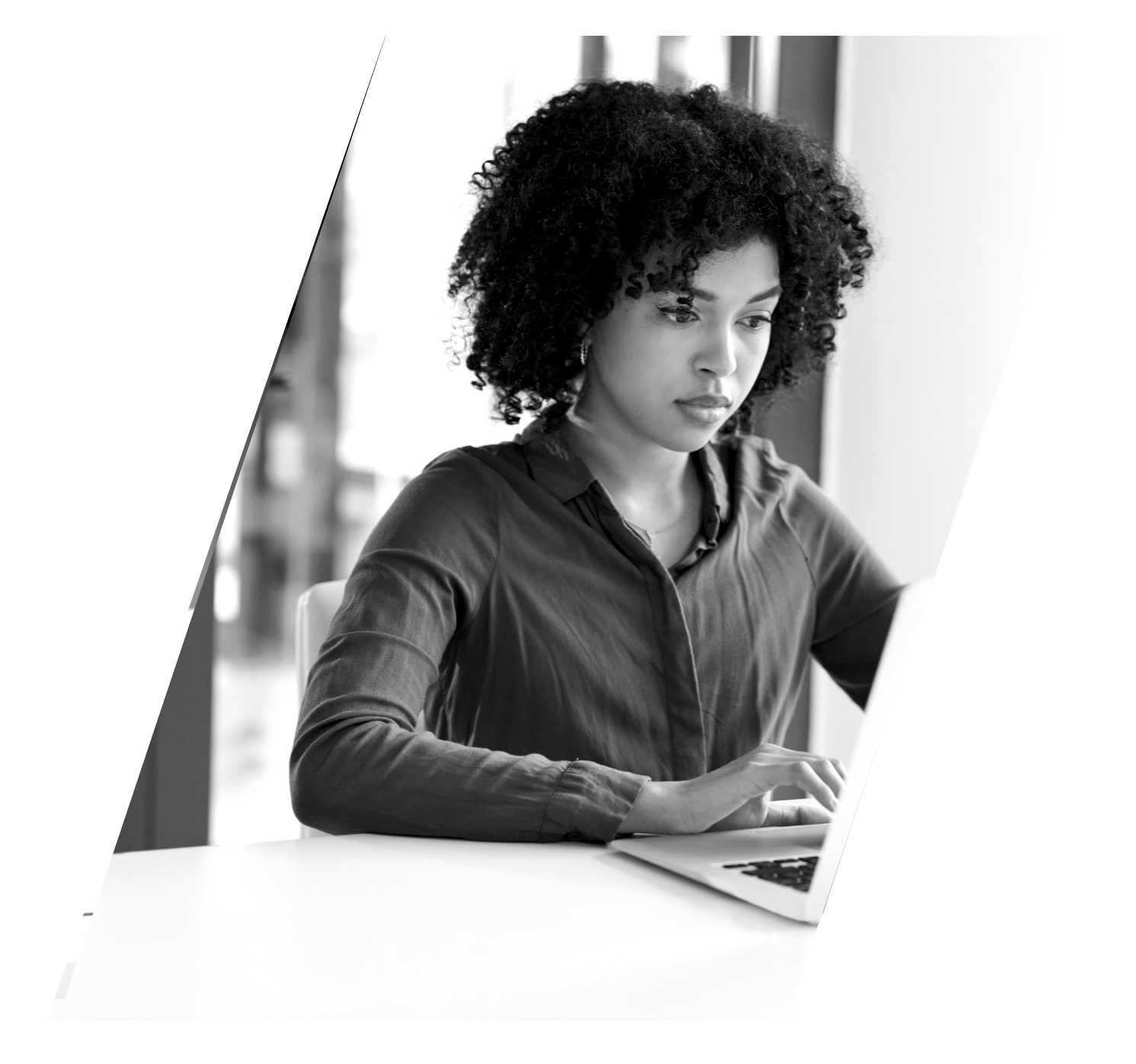 A woman is sitting at a desk using a laptop computer.