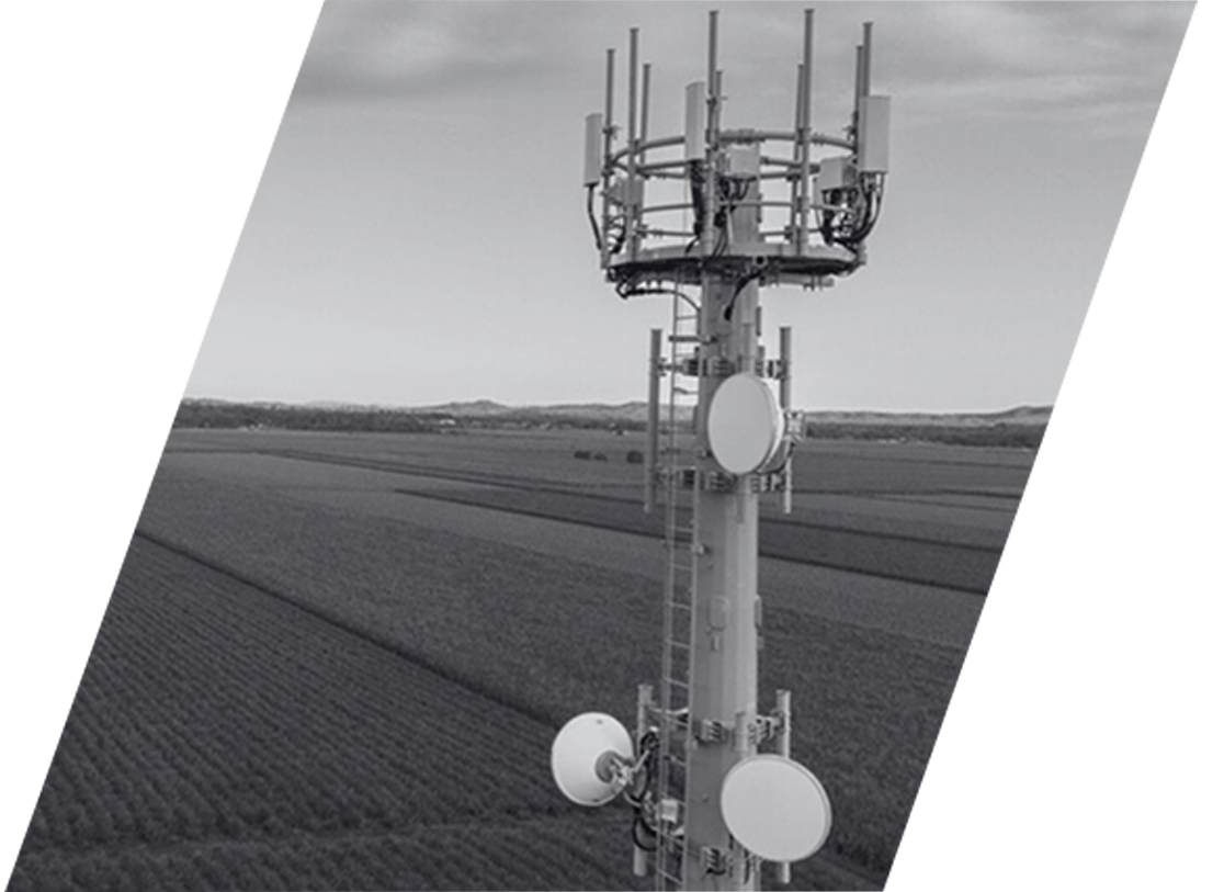 A black and white photo of a cell phone tower in a field