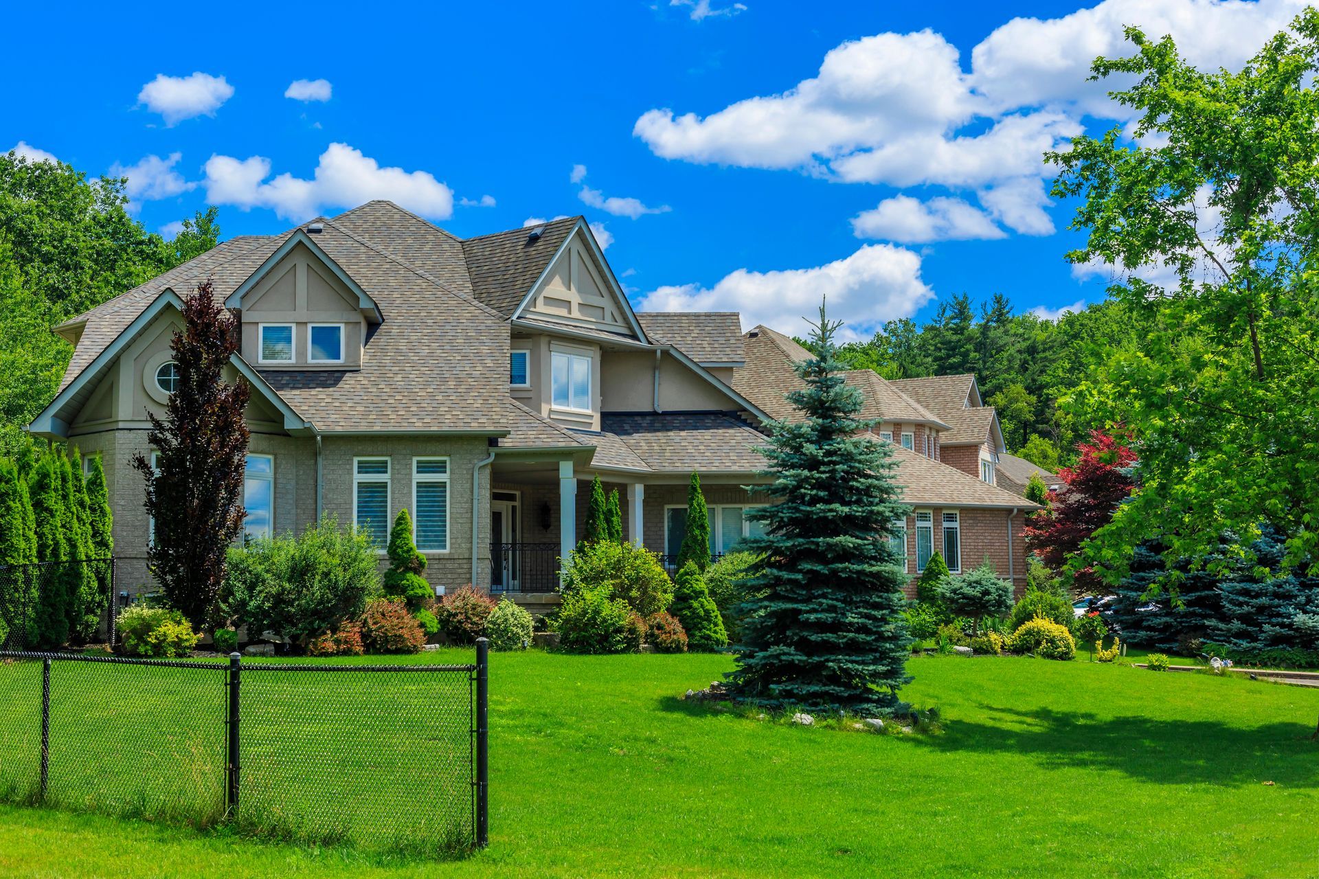 A large house with a chain link fence in front of it and a lawn