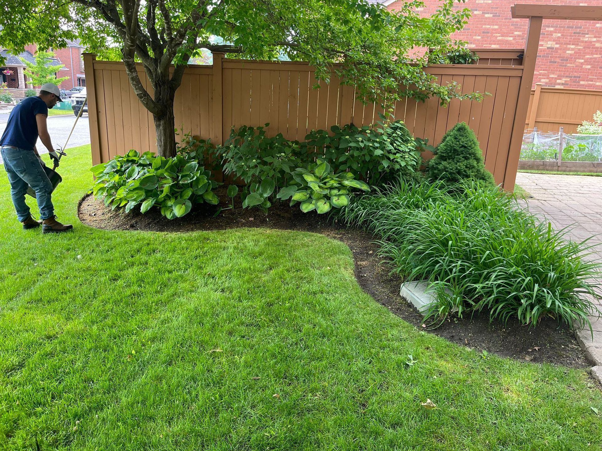 A man is cutting the grass in a yard with a lawn mower.