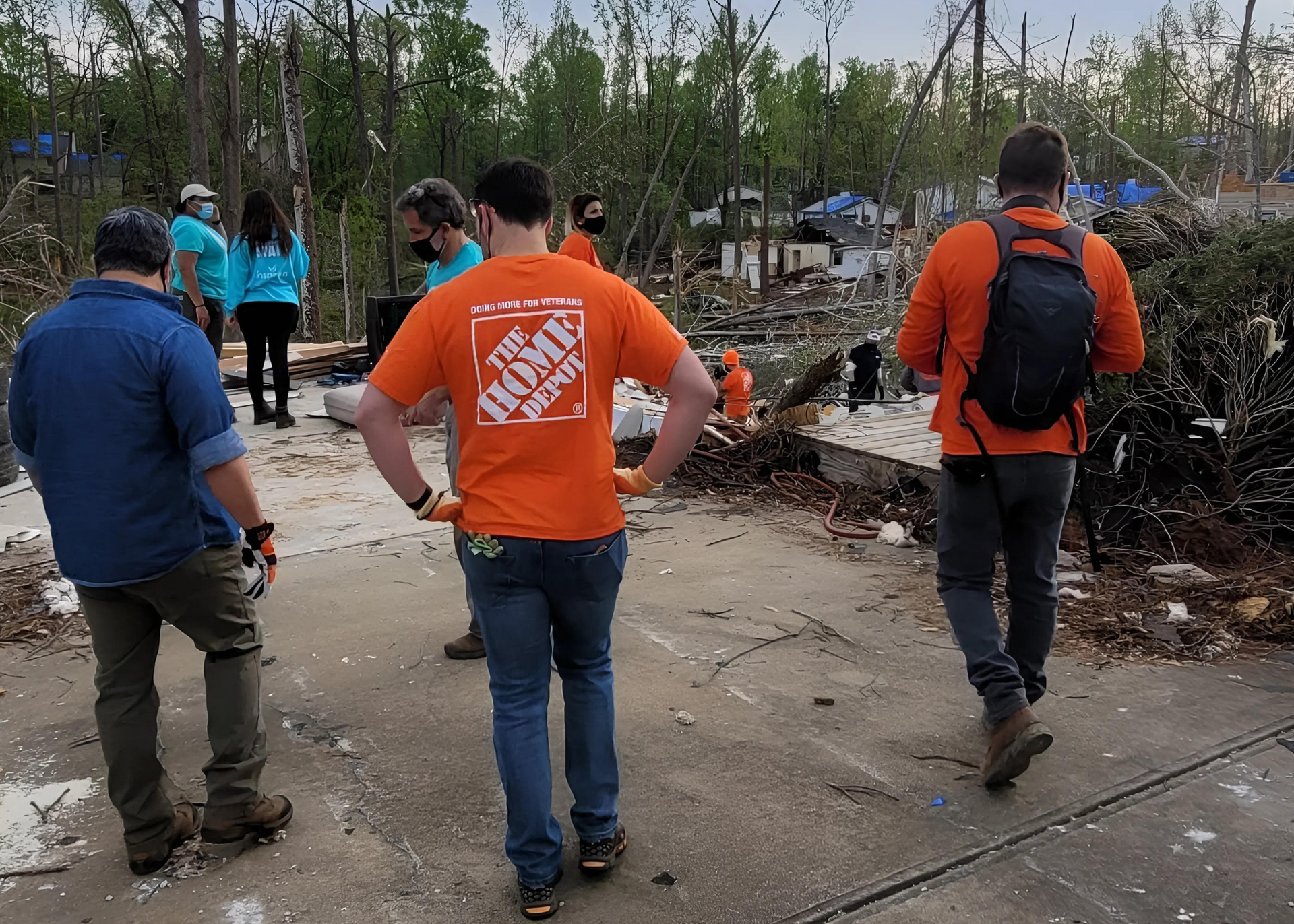 A man wearing an orange home depot shirt is walking down a street