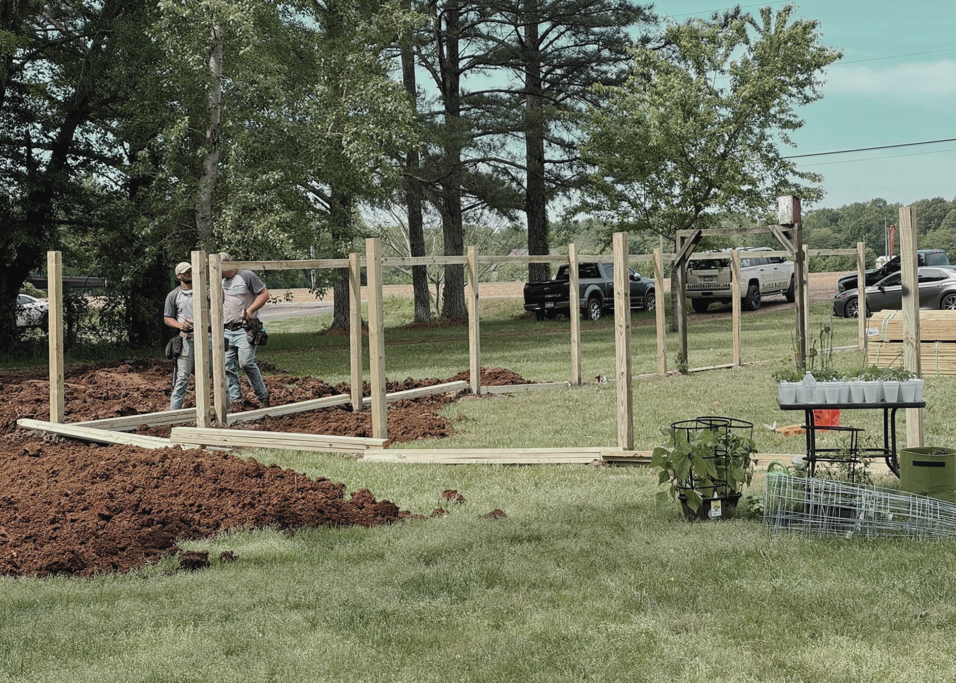 A group of men are working on a wooden fence in a field.