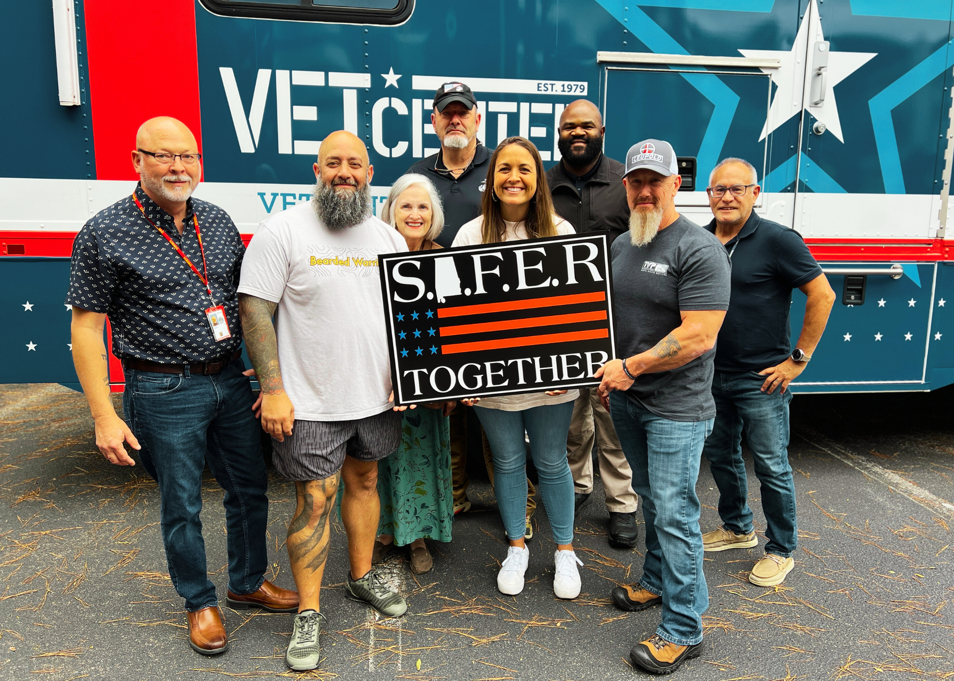 A group of people standing in front of a bus holding a sign that says s.i.fer together.