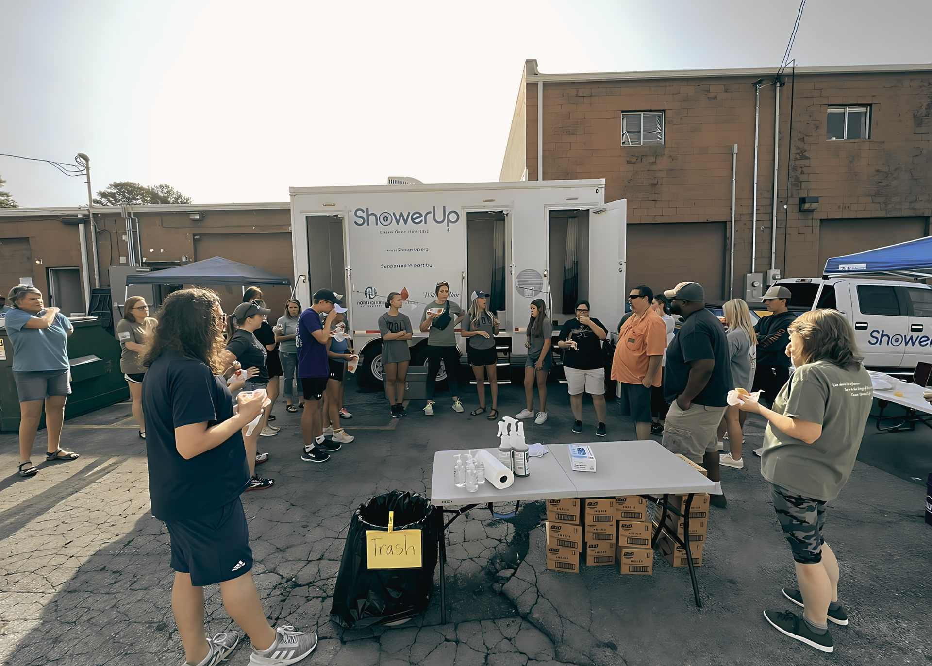 A group of people are standing around a table in front of a trailer that says chamber of commerce